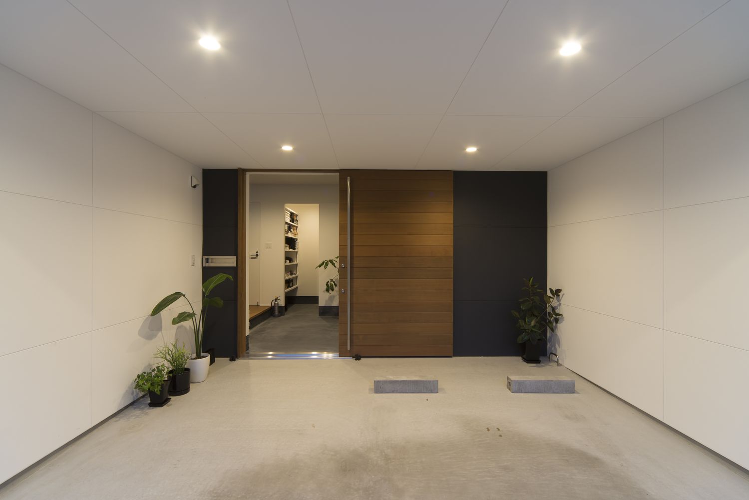 エントランスの手前にある照明付きの広いインナーガレージ・デザイン住宅
