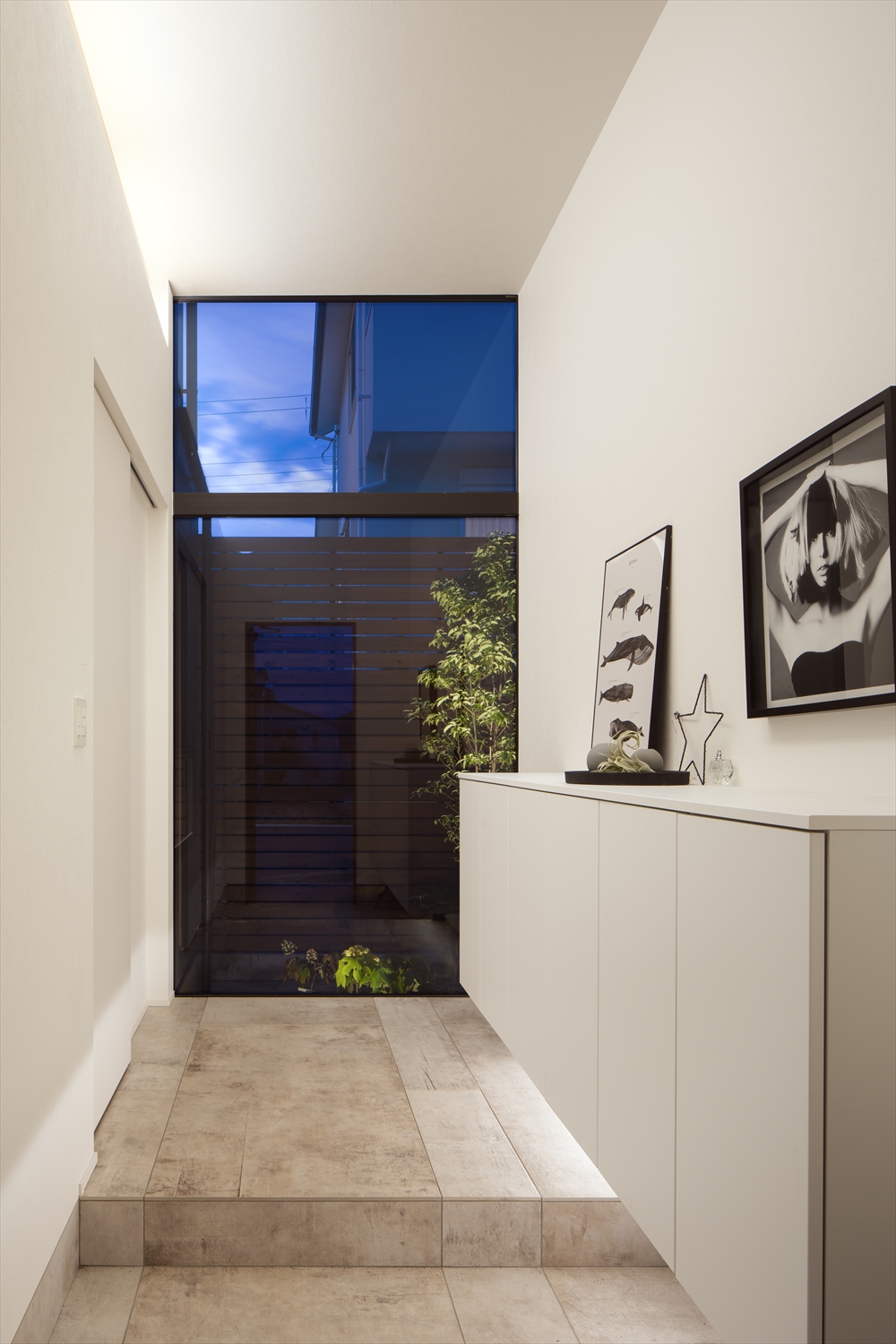 壁に付けたシューズボックスの下に間接照明を取り付けた、正面に窓がある玄関・デザイン住宅 注文住宅・デザイン住宅建築実例_『CASE629 Con』_玄関