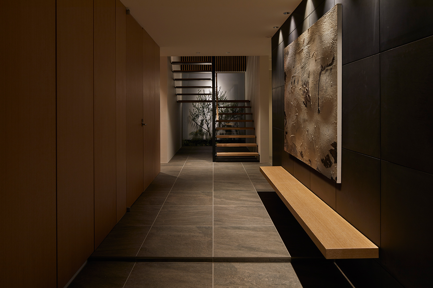 壁付けのベンチがあり、正面には照明に照らされた植栽が見える玄関・デザイン住宅 注文住宅・デザイン住宅建築実例_『CASE632 H邸(社長の邸宅)』_玄関