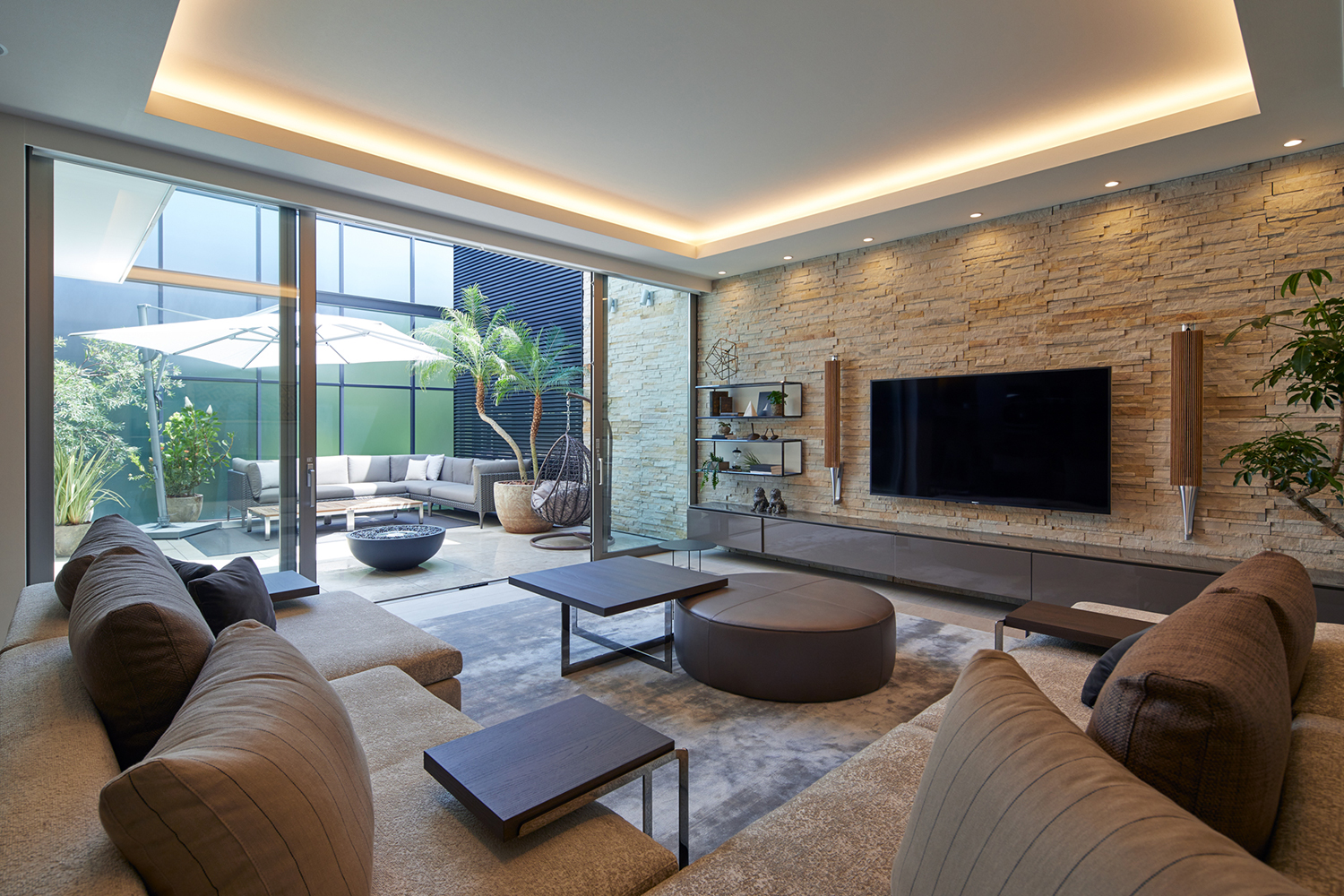 テレビがついている壁が石のアクセントウォールになっているLDK・デザイン住宅 注文住宅・デザイン住宅建築実例_『CASE678 K邸(社長の邸宅)』_LDK