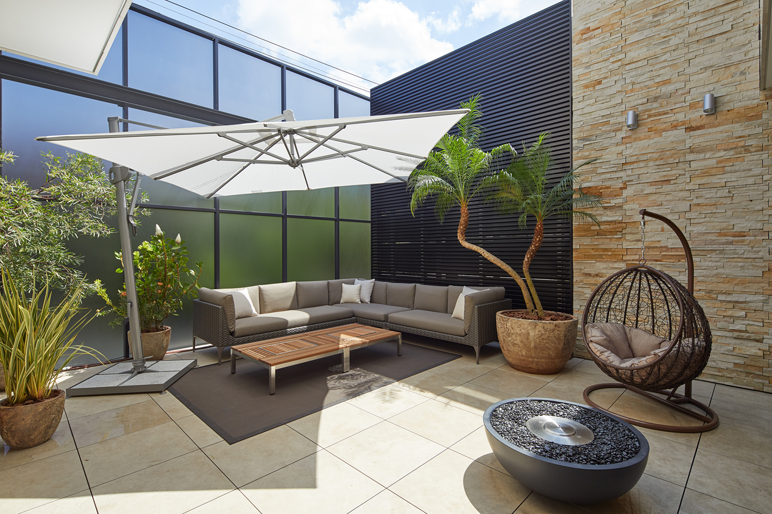 パラソルのついたL字ソファーやハンモックチェアが置かれたバルコニー・デザイン住宅 注文住宅・デザイン住宅建築実例_『CASE678 K邸(社長の邸宅)』_テラス・バルコニー