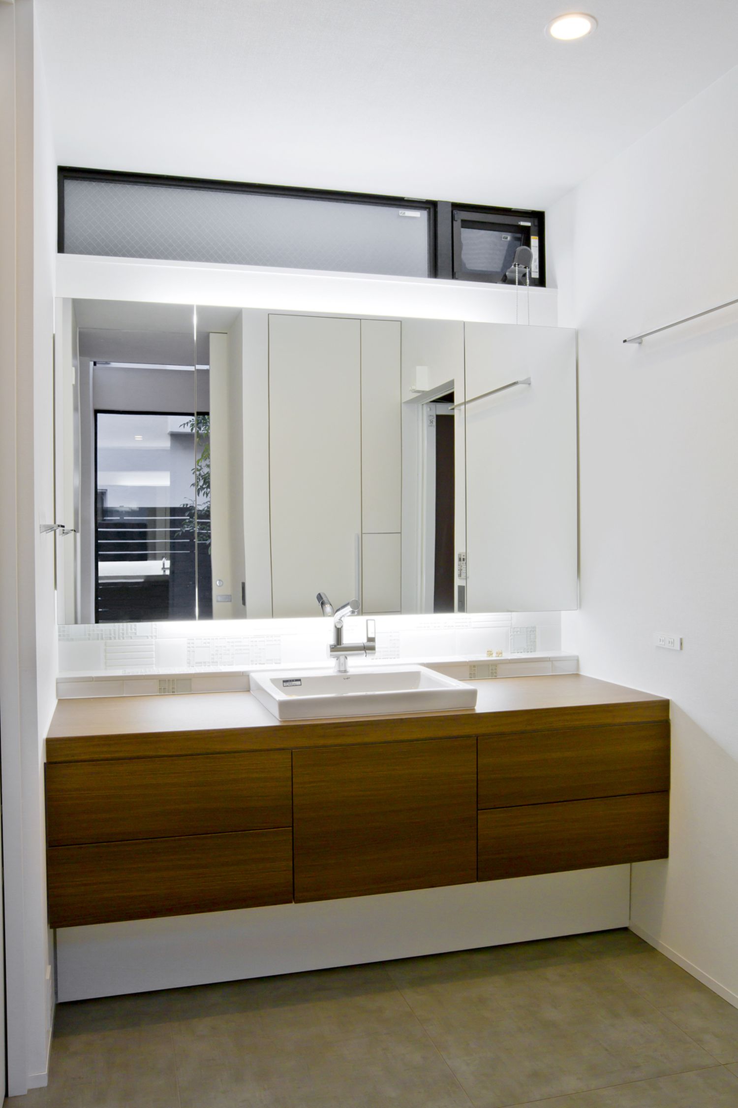 天井近くにスリット窓を取り付けた木の洗面台のシンプルな洗面所・デザイン住宅