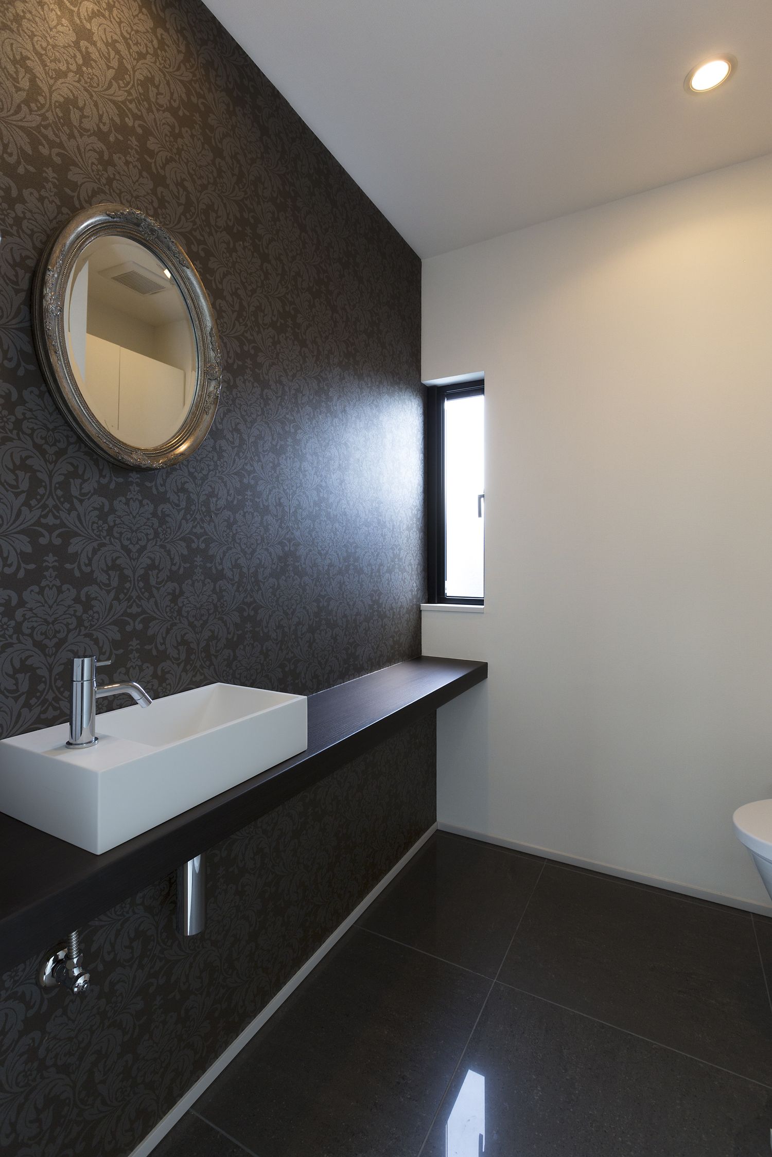 黒いクロスに手洗いカウンターを取り付けた広いトイレ・デザイン住宅