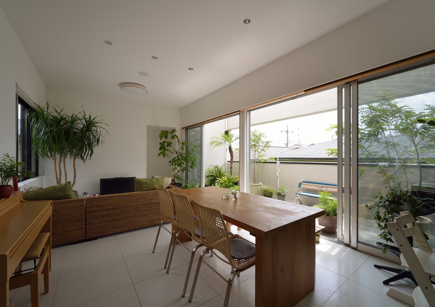観葉植物が沢山あるバルコニーに面した大きな窓付きのLDK・デザイン住宅