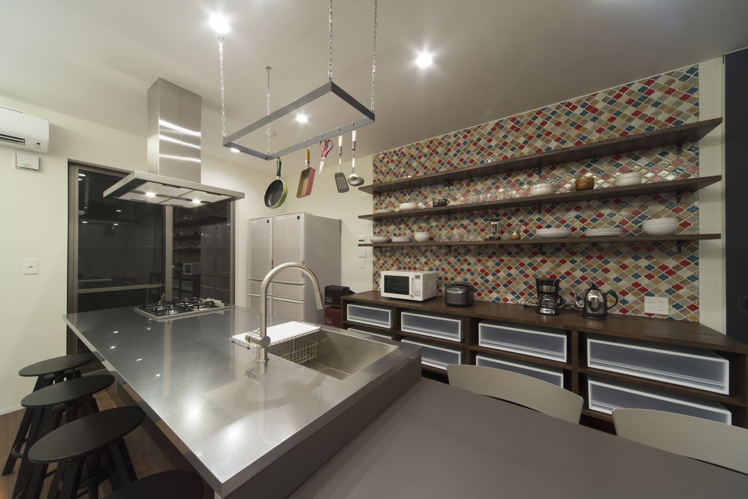 タイルのアクセントウォールに壁付け棚を取り付けた見せる収納があるキッチン・デザイン住宅