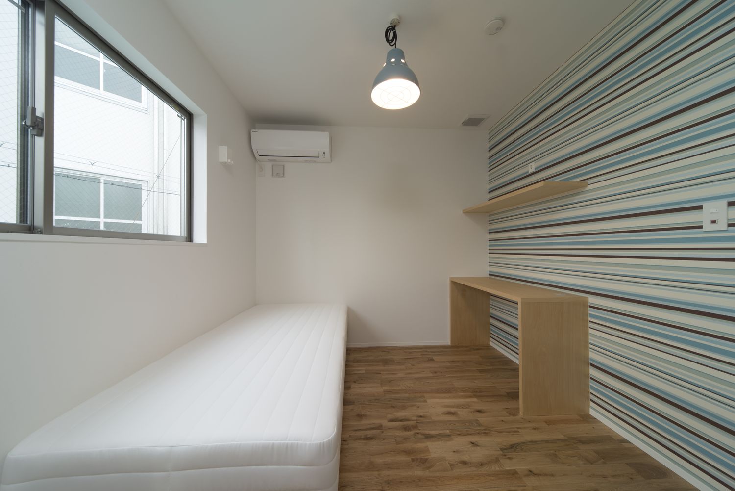 ボーダーのおしゃれなアクセントクロスに壁付けデスクがあるシンプルな寝室・デザイン住宅