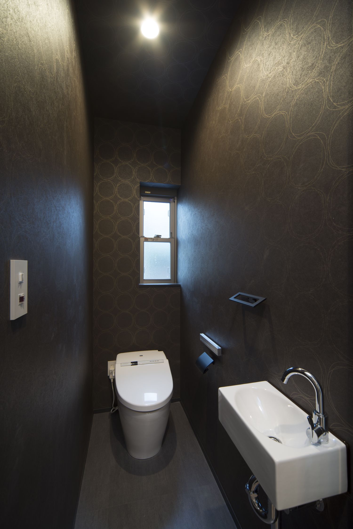 黒い壁で薄型手洗いがある落ち着きのあるトイレ・デザイン住宅