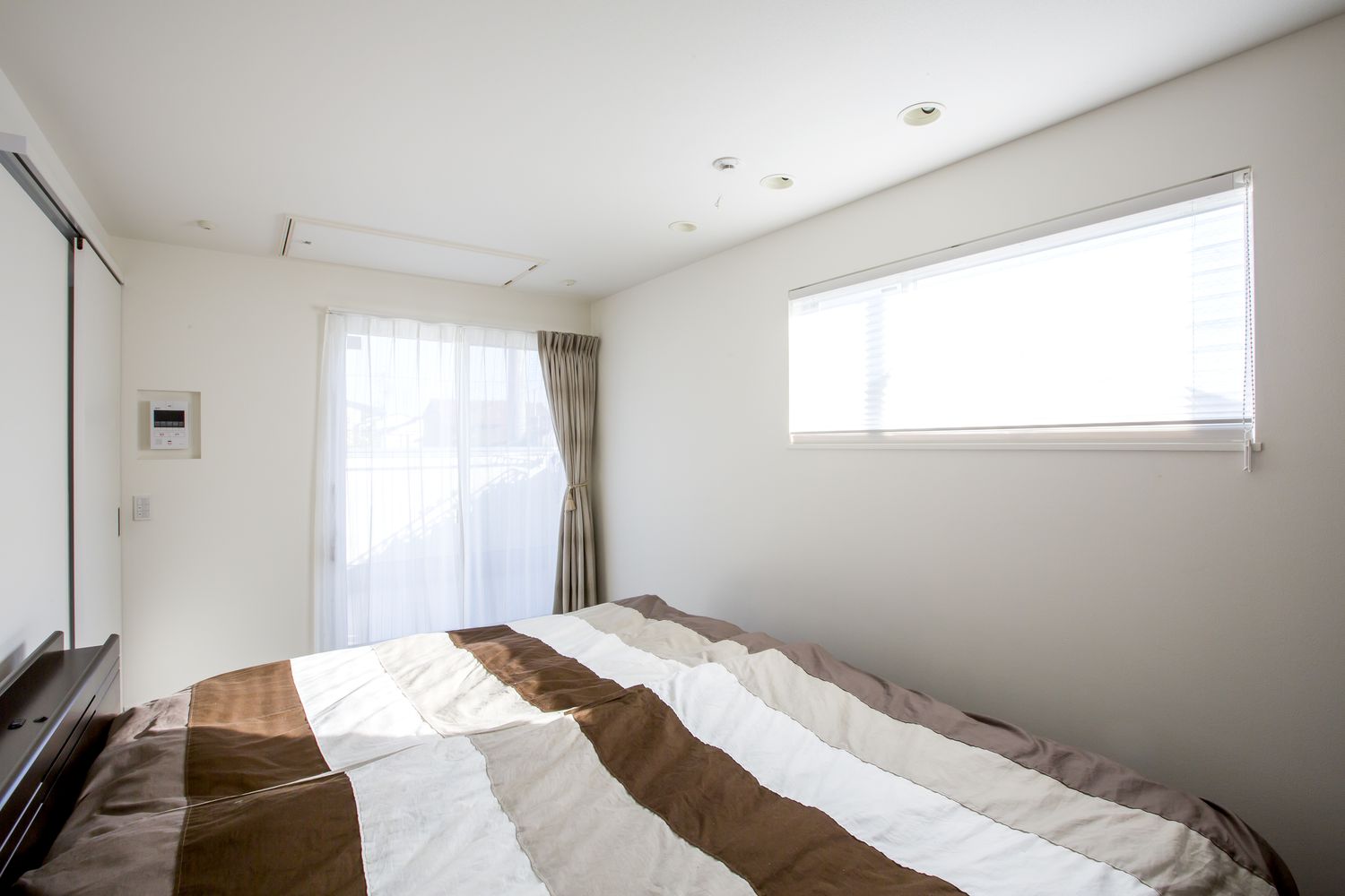 大きな窓とスリット窓が両方あるシンプルで明るい寝室・デザイン住宅