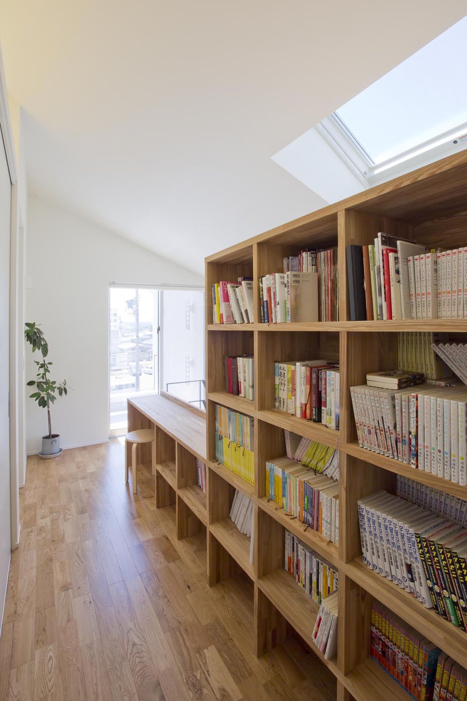 壁際に本棚と机を置いた廊下・デザイン住宅