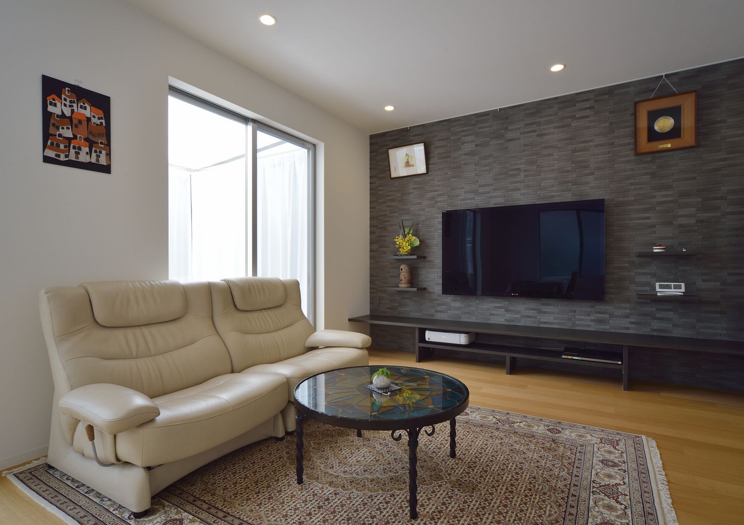 黒いアクセントクロスや白いソファーがあるLDK・デザイン住宅