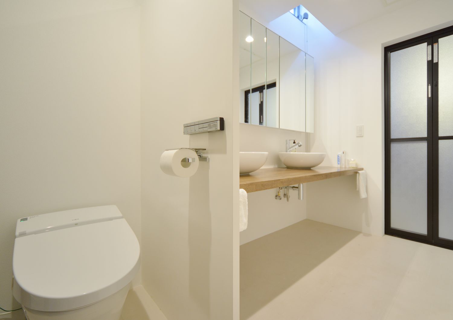 ダブルボウルの洗面所とトイレが一体の空間にあるバスルーム・デザイン住宅