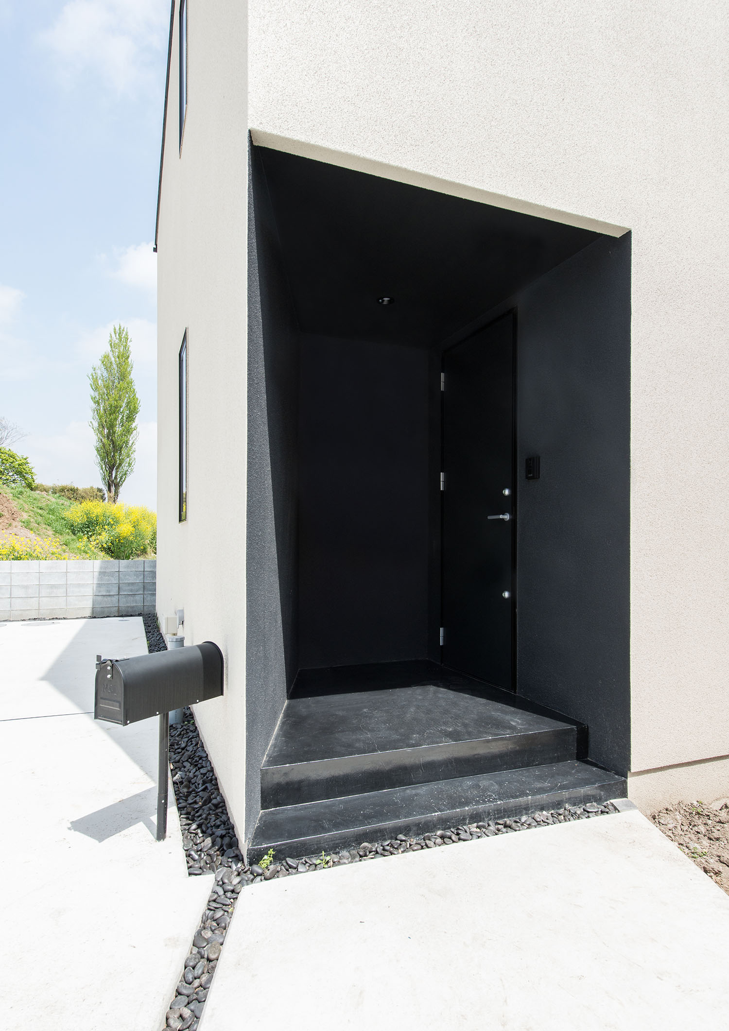 白い外壁をくりぬくようにして作られた、黒い壁と黒い扉の玄関・デザイン住宅 注文住宅・デザイン住宅建築実例_『CASE631 こやのいえ』_外観
