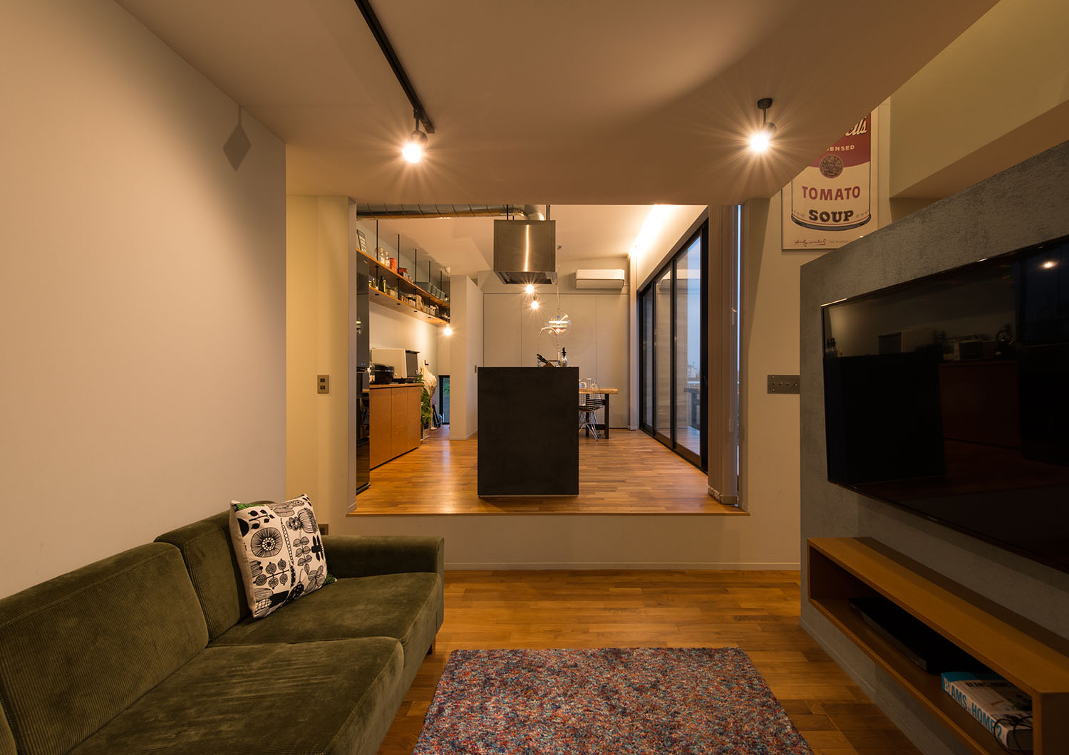 天井にスポットライトが取り付けられたダウンリビングからキッチンを見た様子・デザイン住宅 注文住宅・デザイン住宅建築実例_『CASE631 こやのいえ』_LDK