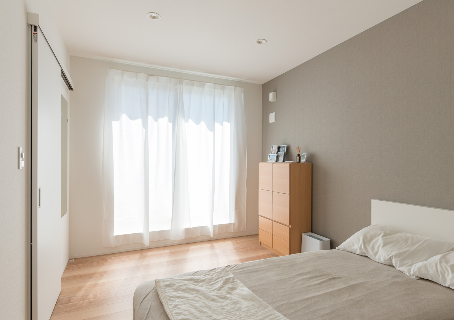 シーツとアクセントクロスがベージュで統一された窓付きの寝室・デザイン住宅 注文住宅・デザイン住宅建築実例_『CASE638 「BLACK BOX」』_寝室