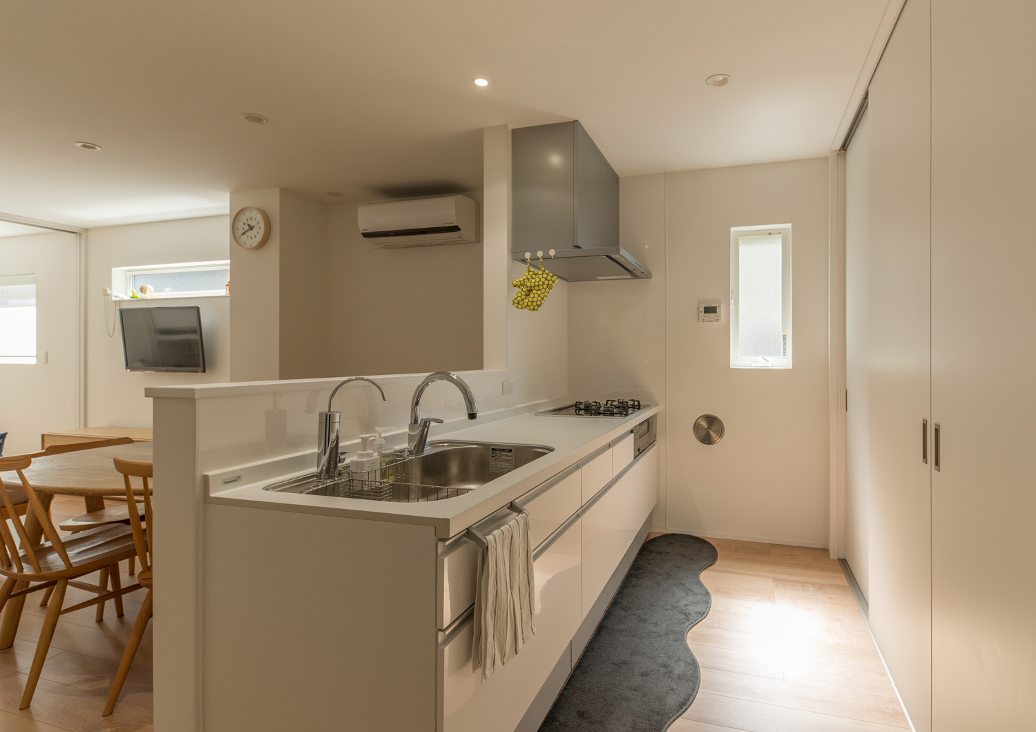 カップボードが扉で隠された、腰壁付きの白いペニンシュラキッチン・デザイン住宅 注文住宅・デザイン住宅建築実例_『CASE638 「BLACK BOX」』_キッチン