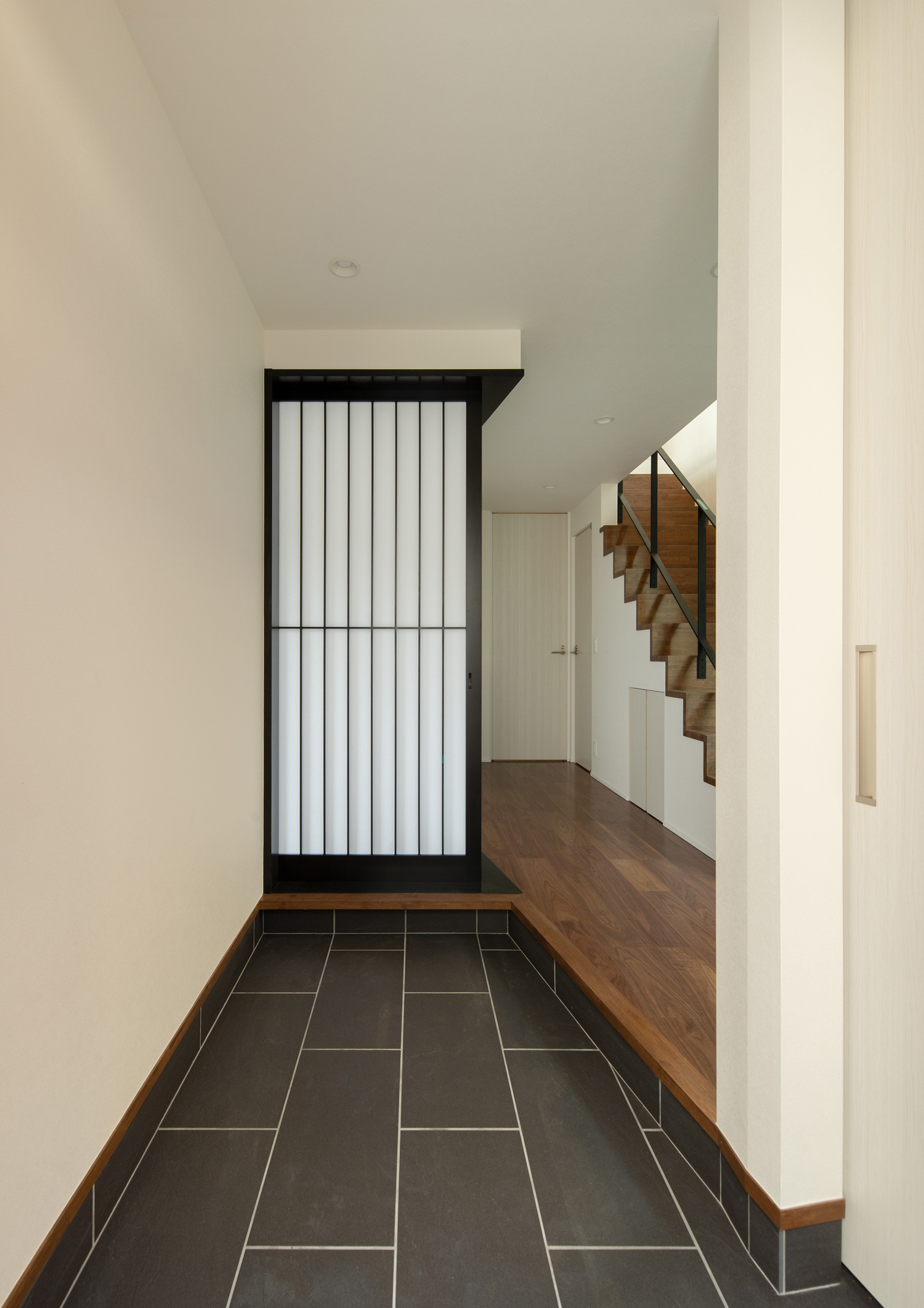 正面に黒枠の障子が見える、黒いタイルの玄関・デザイン住宅 注文住宅・デザイン住宅建築実例_『CASE639 Wall Side』_玄関