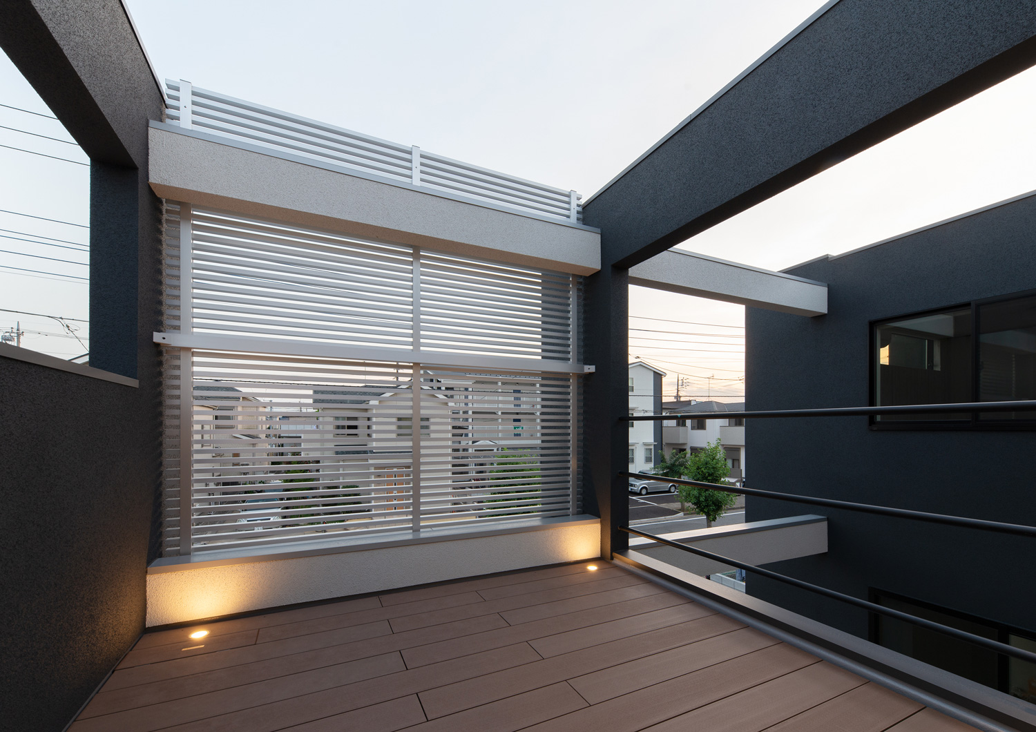 金属のルーバーの目隠しがあり、足元に照明が取り付けられたウッドデッキのバルコニー・デザイン住宅 注文住宅・デザイン住宅建築実例_『CASE639 Wall Side』_テラス・バルコニー