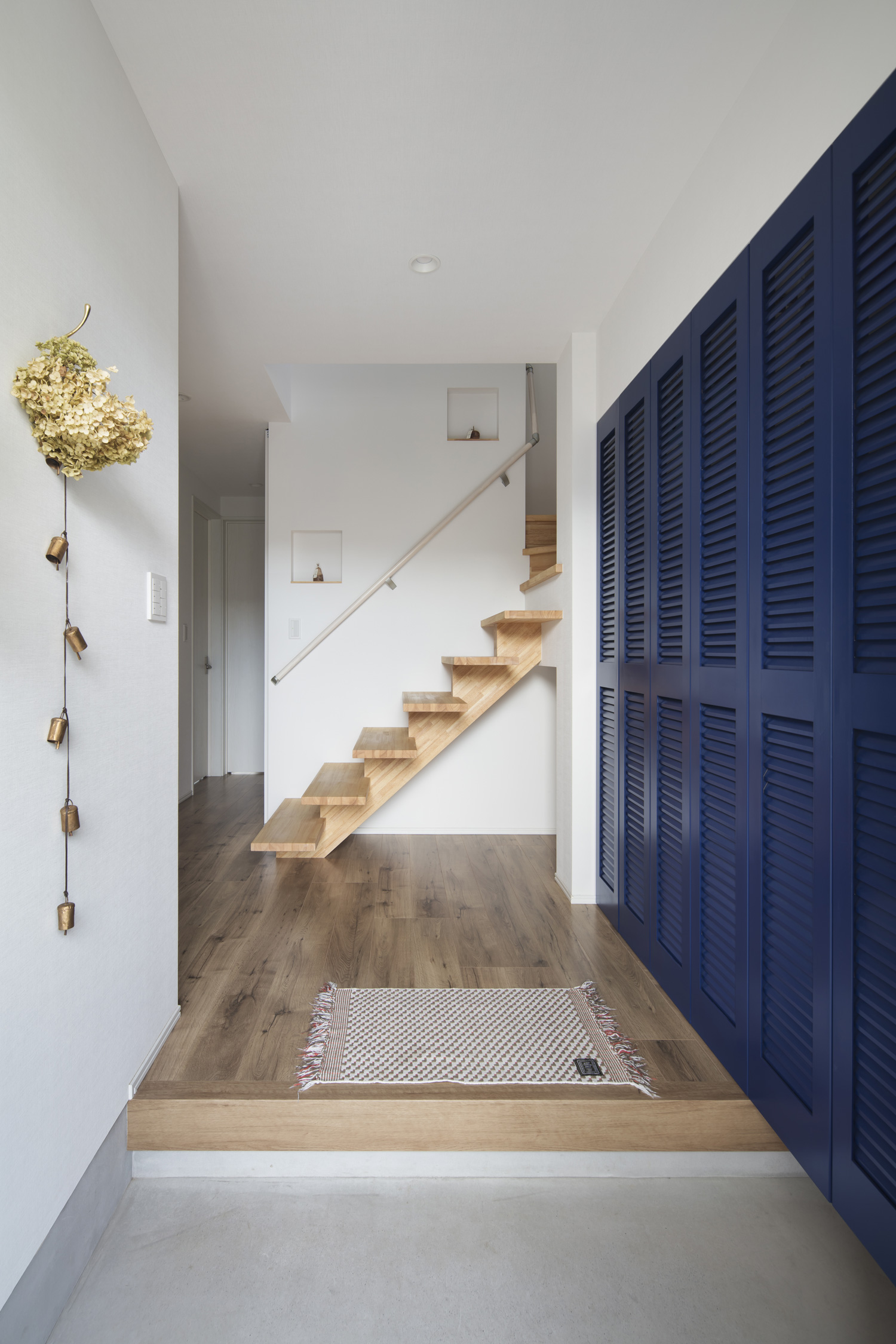 脇に青い扉があり、正面に木製のスケルトン階段がある玄関・デザイン住宅 注文住宅・デザイン住宅建築実例_『CASE640 nature』_玄関