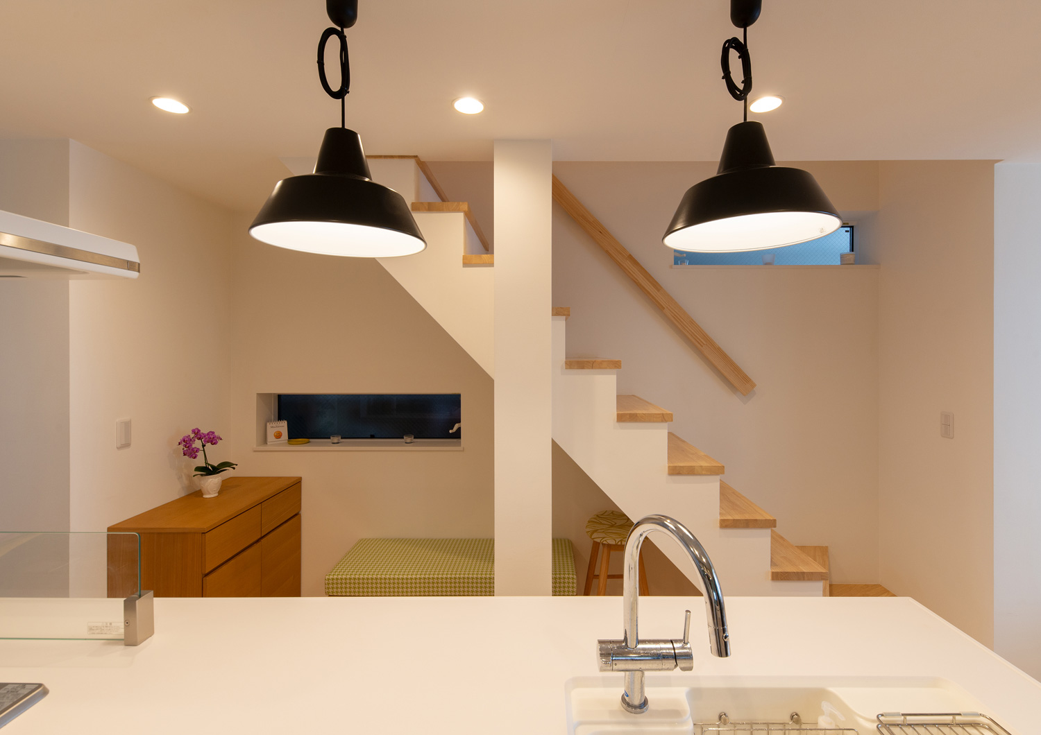 白いキッチンの前に見える階段とスリット窓・デザイン住宅 注文住宅・デザイン住宅建築実例_『CASE641 だんだん』_キッチン