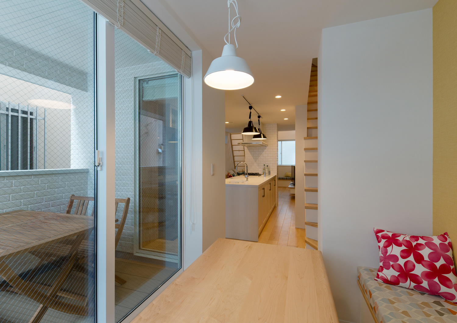 ベランダの前にある木のテーブルがペンダントライトに照らされる様子・デザイン住宅 注文住宅・デザイン住宅建築実例_『CASE641 だんだん』_LDK