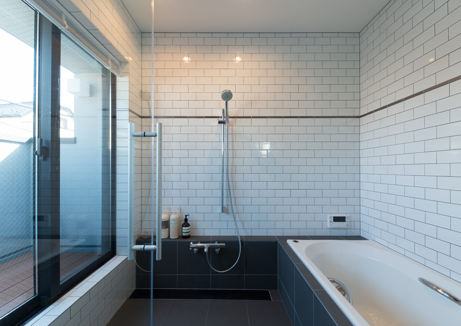 タイルの壁で、バルコニーと繋がる浴室・デザイン住宅 注文住宅・デザイン住宅建築実例_『CASE643 だて窓のハウス』_浴室・洗面所