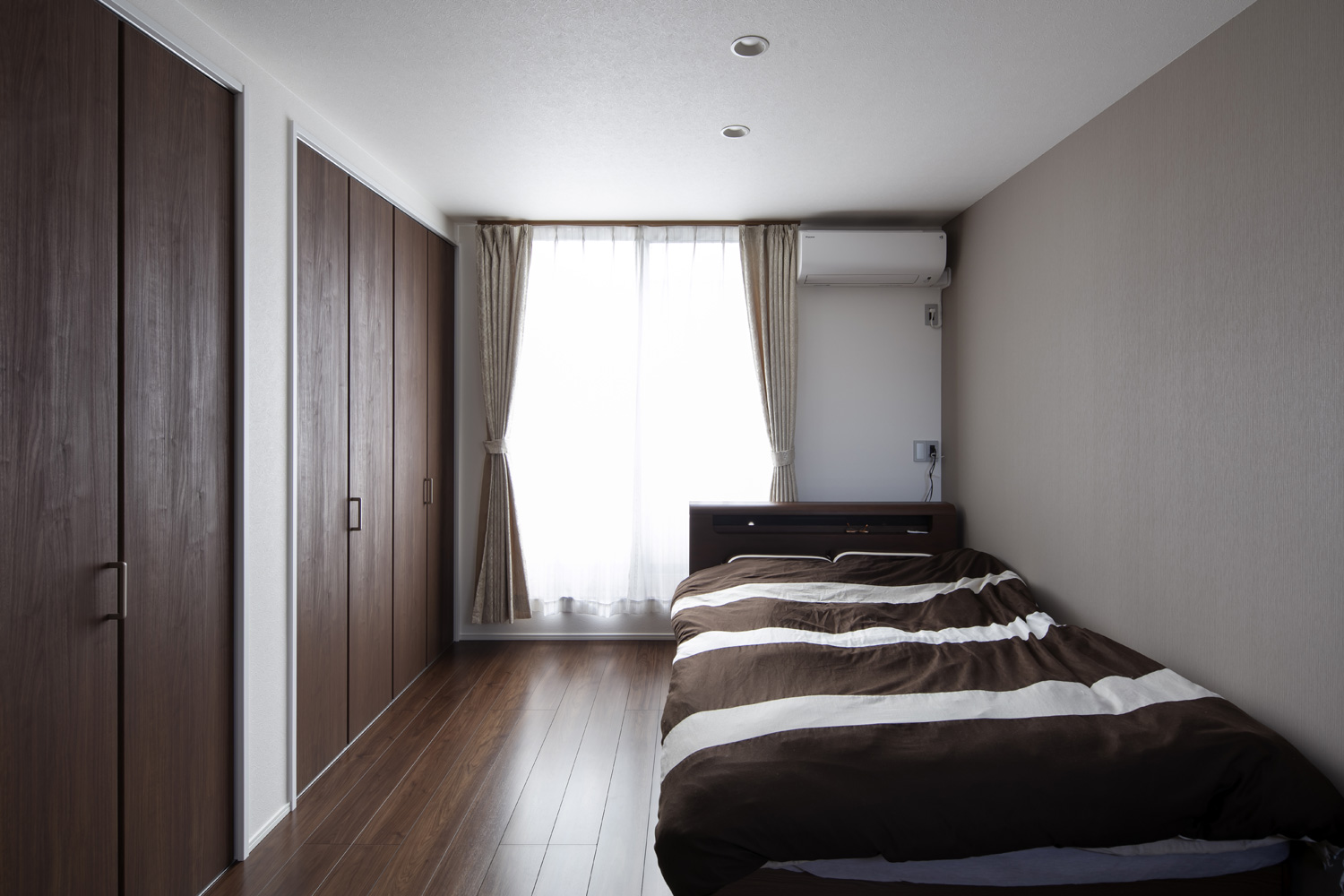 フローリングと建具とベッドをダークブラウンで統一した、窓のある寝室・デザイン住宅 注文住宅・デザイン住宅建築実例_『CASE644 Oasis』_寝室