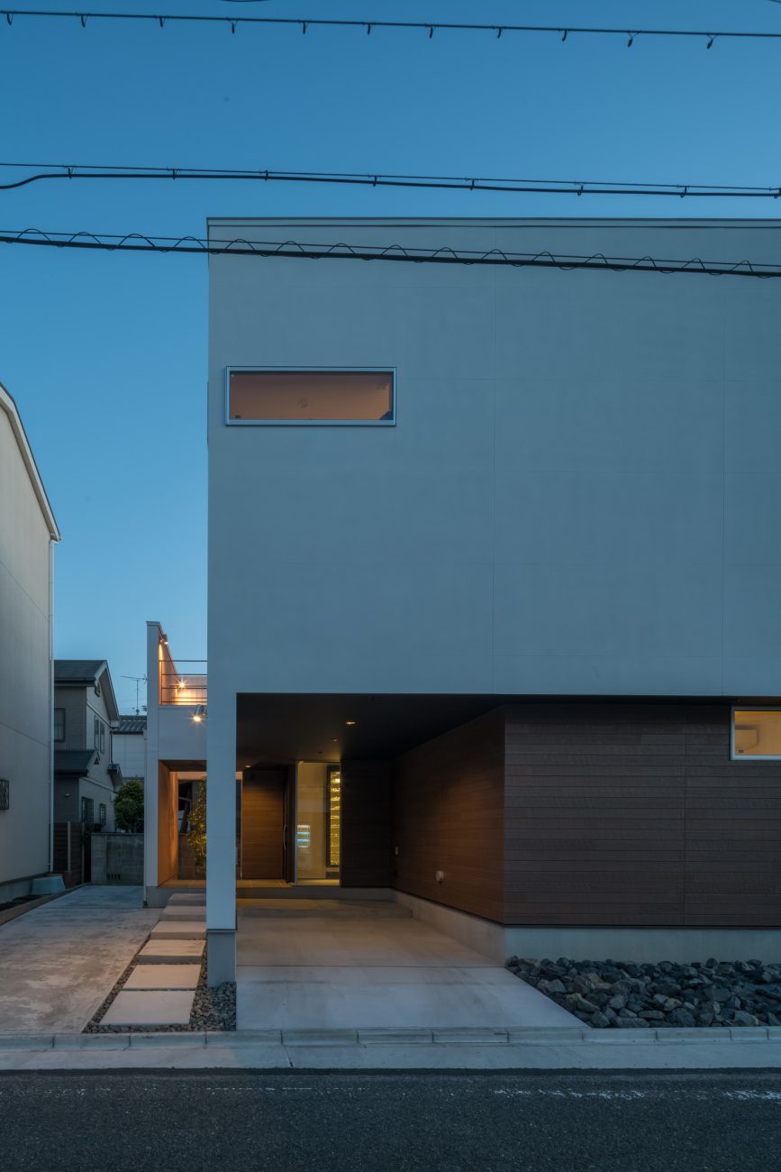 コンクリートのアプローチの先にある玄関ポーチが照明で照らされる様子・デザイン住宅 注文住宅・デザイン住宅建築実例_『CASE645 フレームハウス』_外観