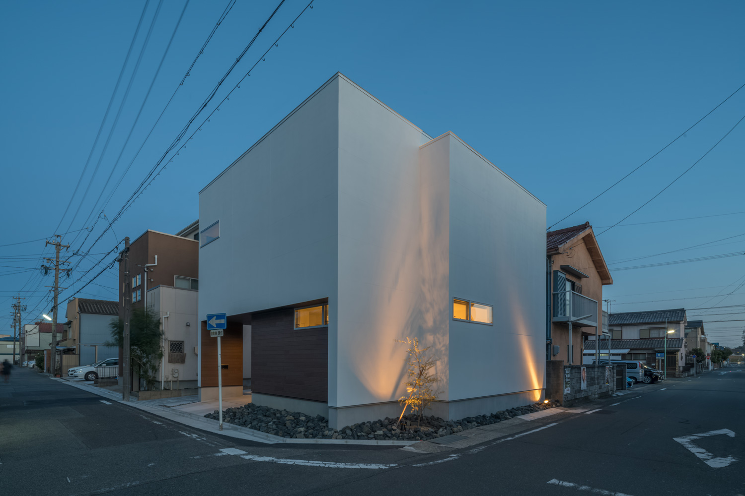 角地に建つ住宅の白い外壁に植栽がライトアップされている様子・デザイン住宅 注文住宅・デザイン住宅建築実例_『CASE645 フレームハウス』_外観