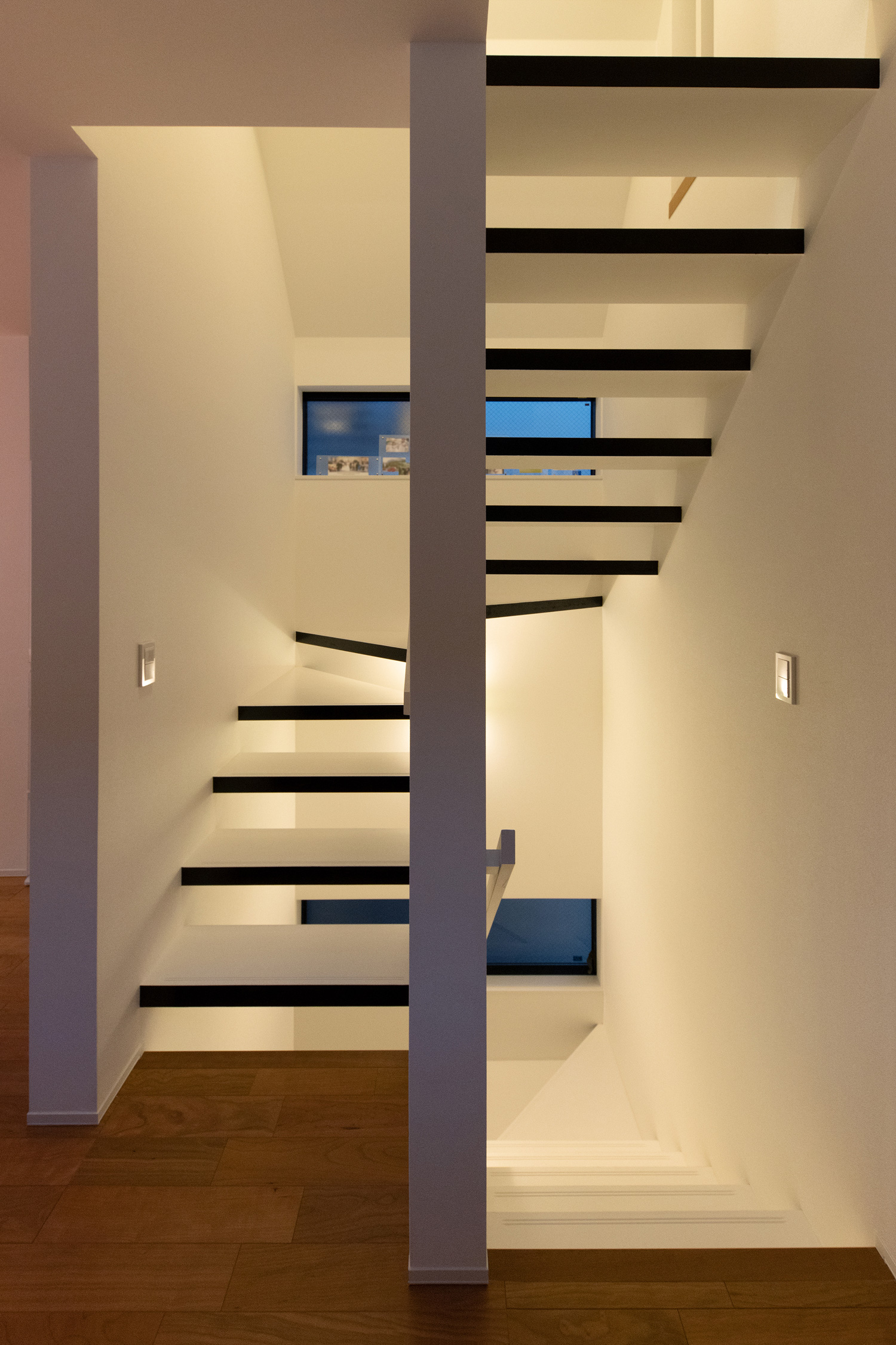 壁に取り付けられた照明の光がスケルトン階段の間から漏れる様子・デザイン住宅 注文住宅・デザイン住宅建築実例_『CASE648 白鍵の家』_階段