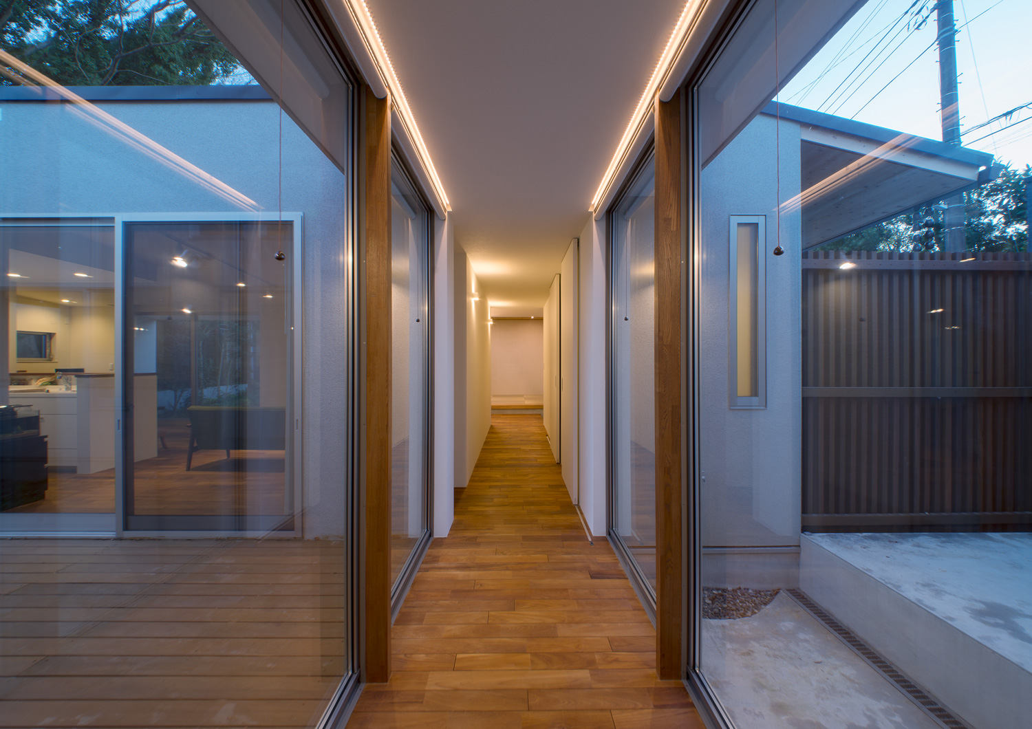 大開口窓に挟まれた、窓際に直線の照明を取り付けたフローリングの廊下・デザイン住宅 注文住宅・デザイン住宅建築実例_『CASE649 光の通り道』_テラス・バルコニー