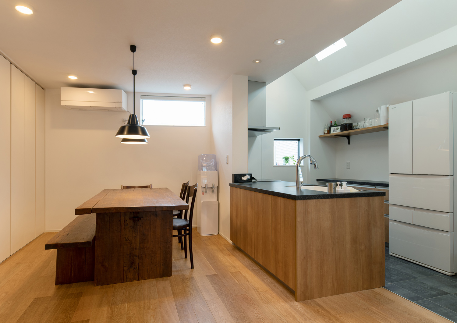 木のペニンシュラキッチンの前に一枚板のダイニングテーブルが置かれたLDK・デザイン住宅 注文住宅・デザイン住宅建築実例_『CASE651 New_tral House』_LDK