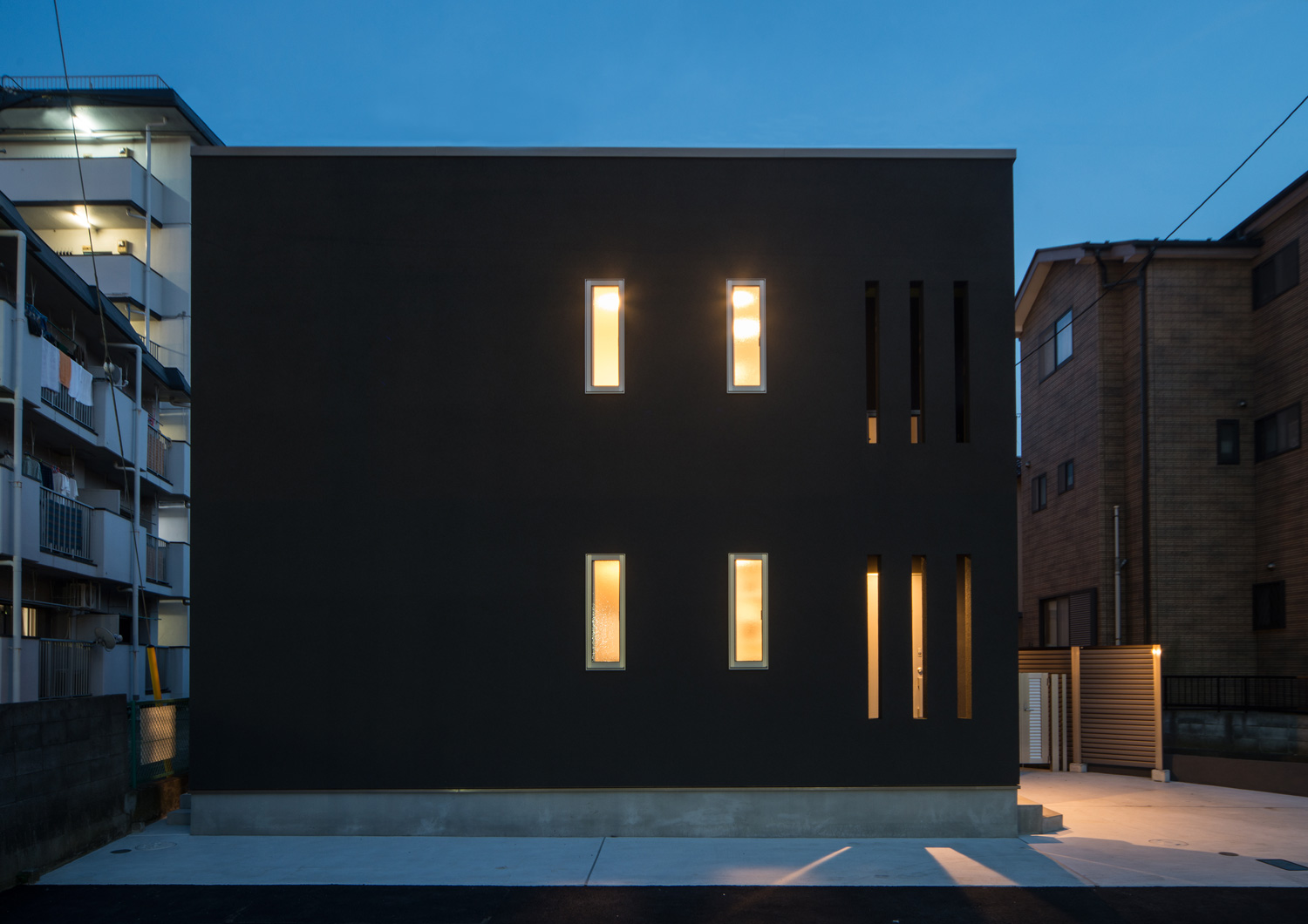 キューブ状の外観に取り付けられた小さな窓から光が漏れる様子・デザイン住宅 注文住宅・デザイン住宅建築実例_『CASE652 2つの吹抜けを持つ家。』_外観