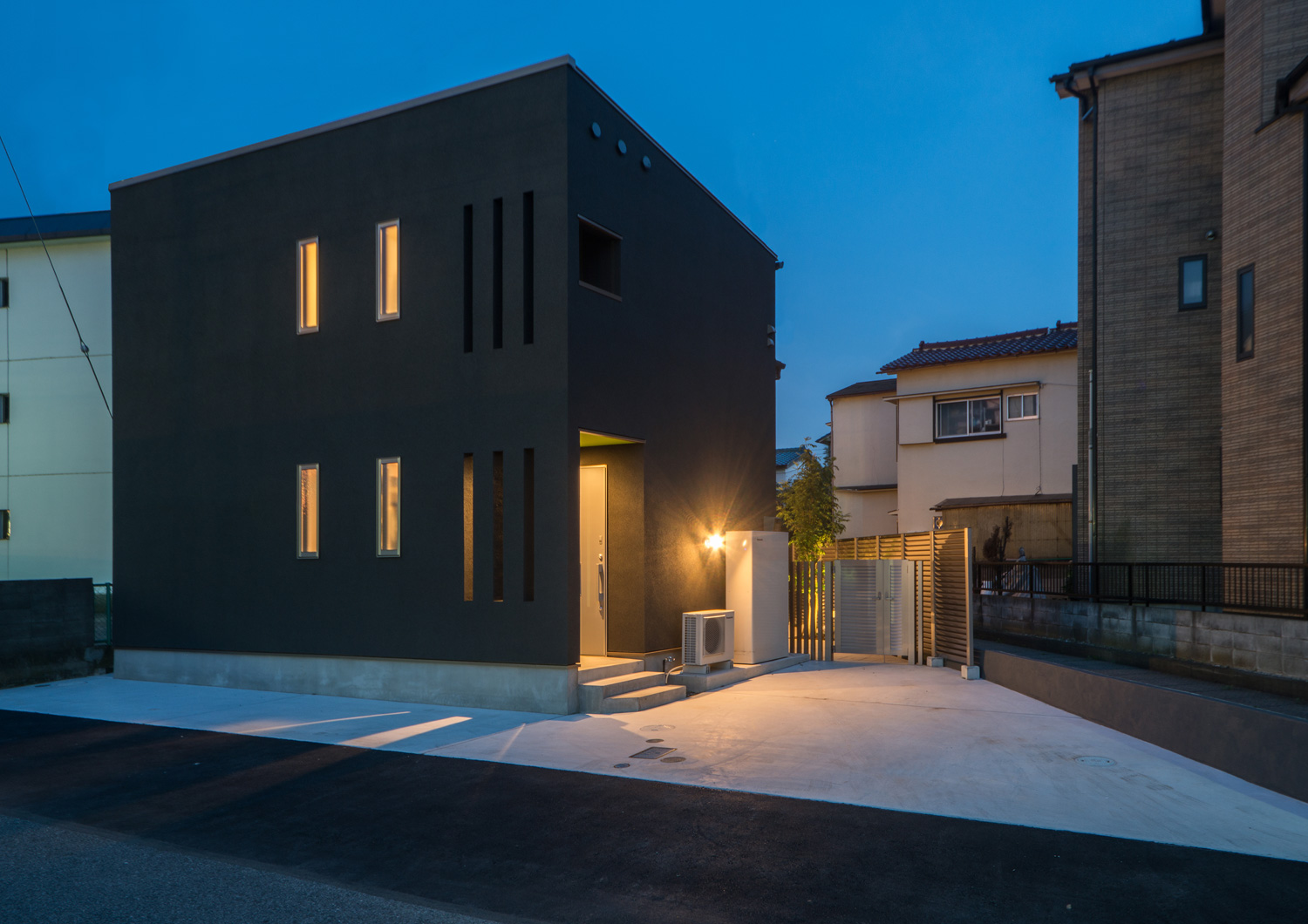 小さな窓があるキューブ状の住まいの玄関にライトが取り付けられている住まい・デザイン住宅 注文住宅・デザイン住宅建築実例_『CASE652 2つの吹抜けを持つ家。』_外観