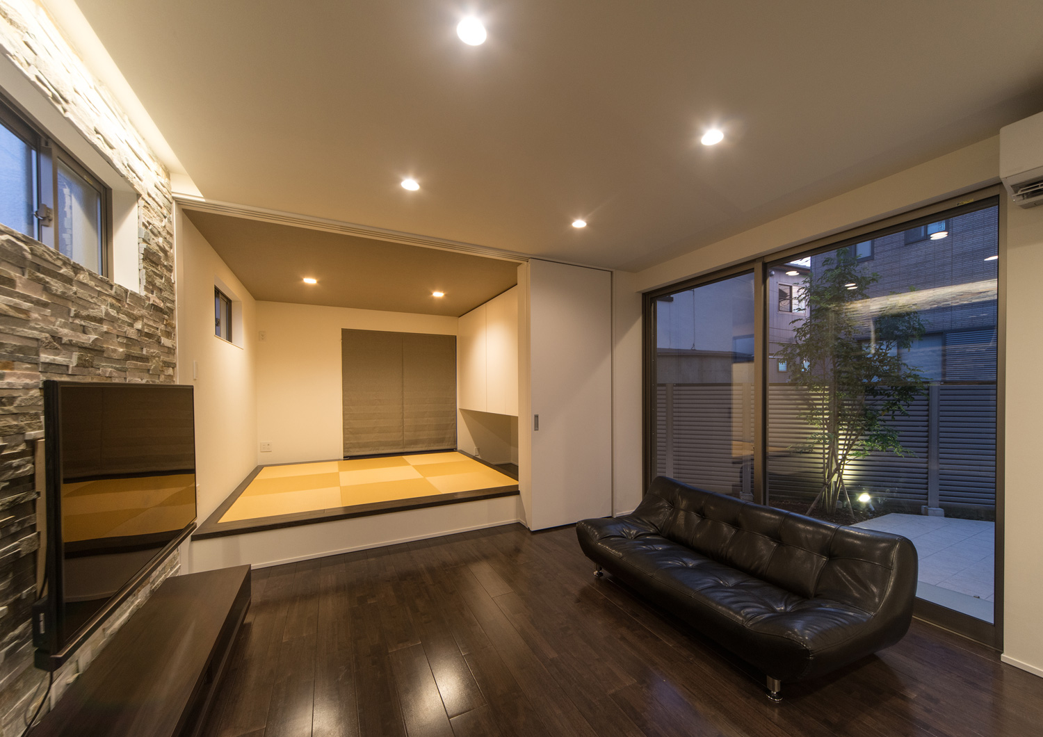 天井のダウンライトやアクセントウォールのそばの間接照明に照らされたLDK・デザイン住宅 注文住宅・デザイン住宅建築実例_『CASE652 2つの吹抜けを持つ家。』_LDK