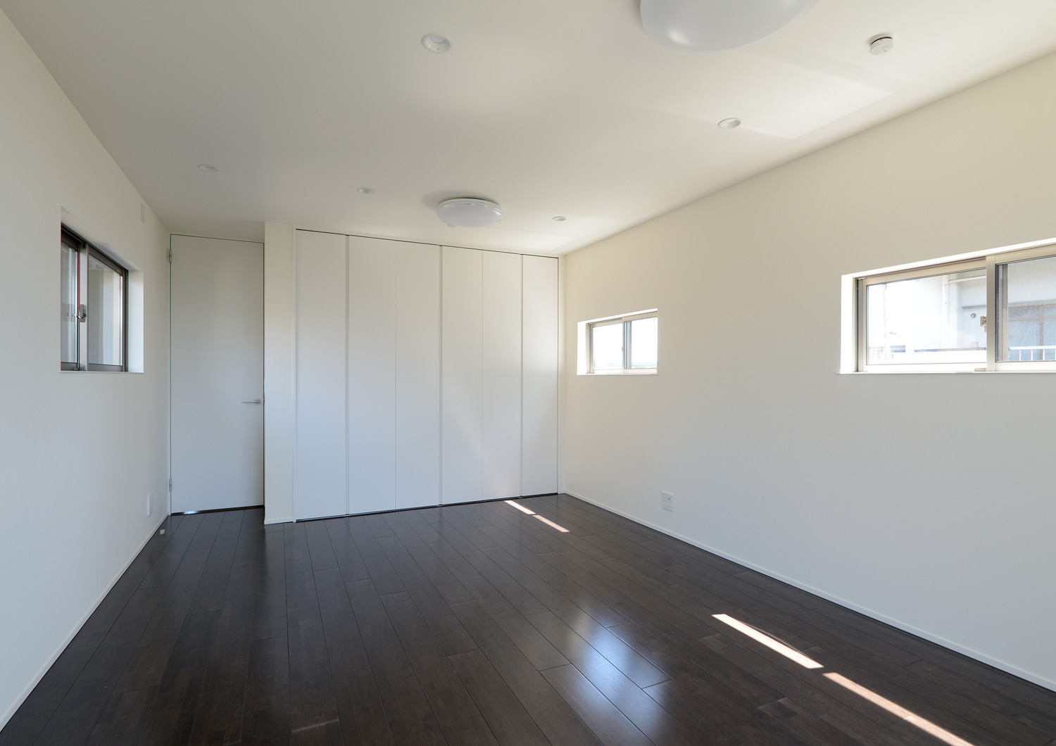 スリット窓が設けられた濃い色のフローリングの個室・デザイン住宅 注文住宅・デザイン住宅建築実例_『CASE652 2つの吹抜けを持つ家。』_寝室