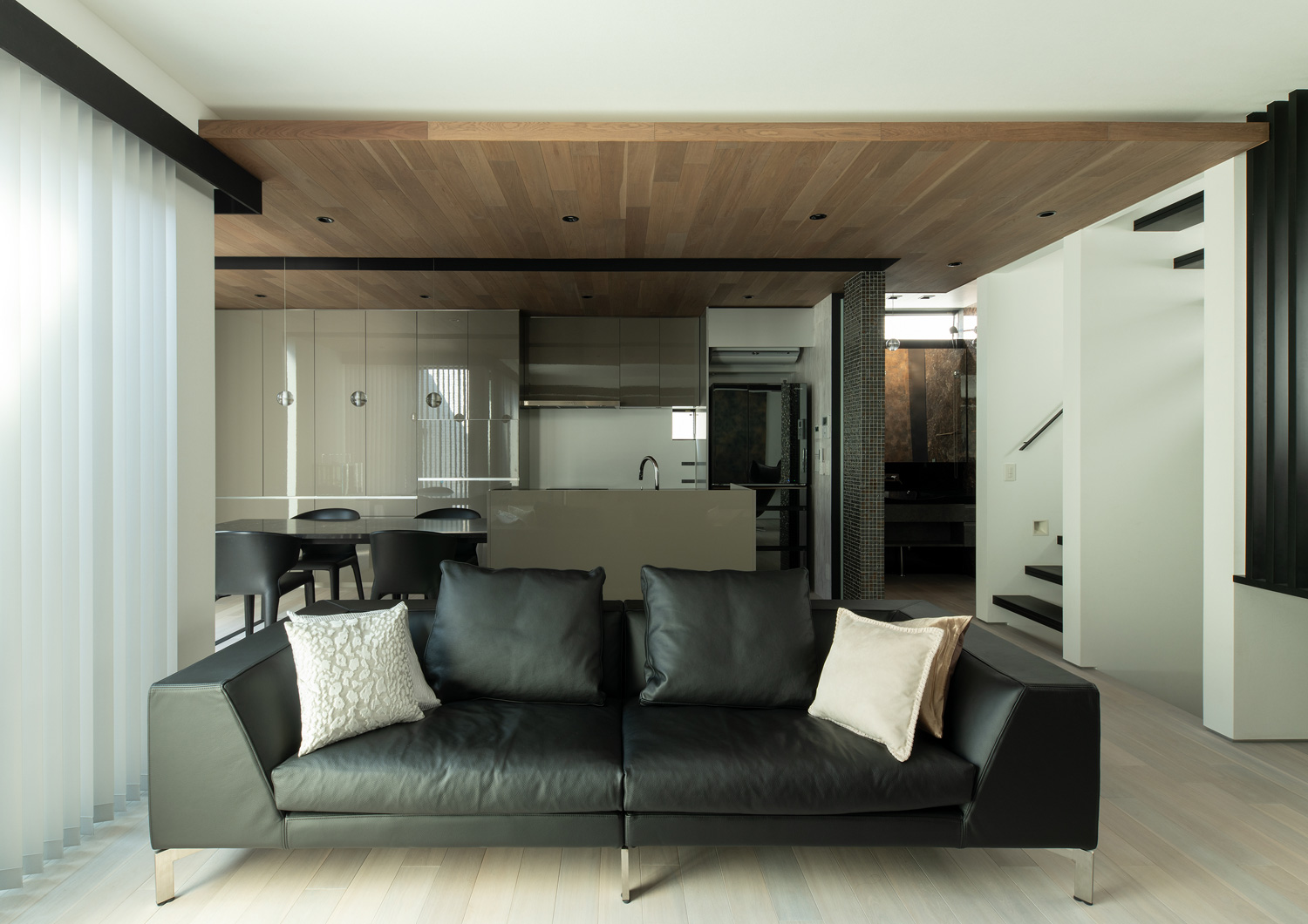 黒いソファーがあるリビングから、木目の下がり天井のあるキッチンが見える様子・デザイン住宅 注文住宅・デザイン住宅建築実例_『CASE653 せんのいえ』_LDK