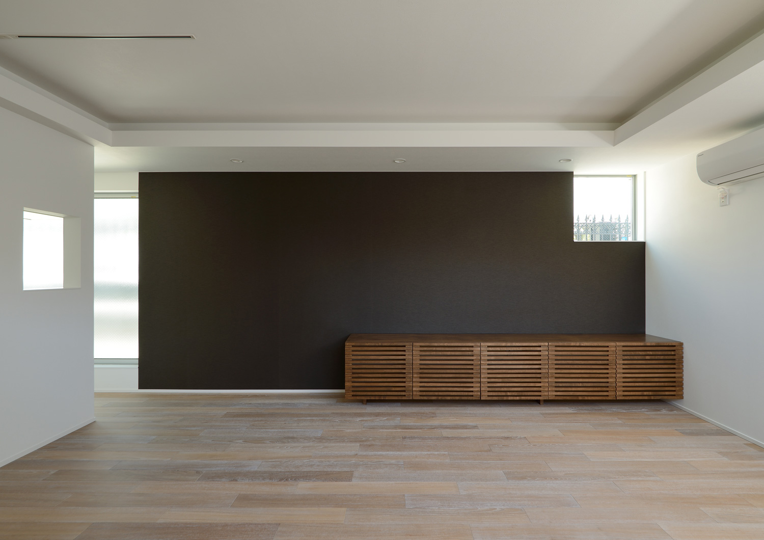 黒い壁の前に木製の棚が置かれたフローリングのLDK・デザイン住宅 注文住宅・デザイン住宅建築実例_『CASE654 circulating』_LDK