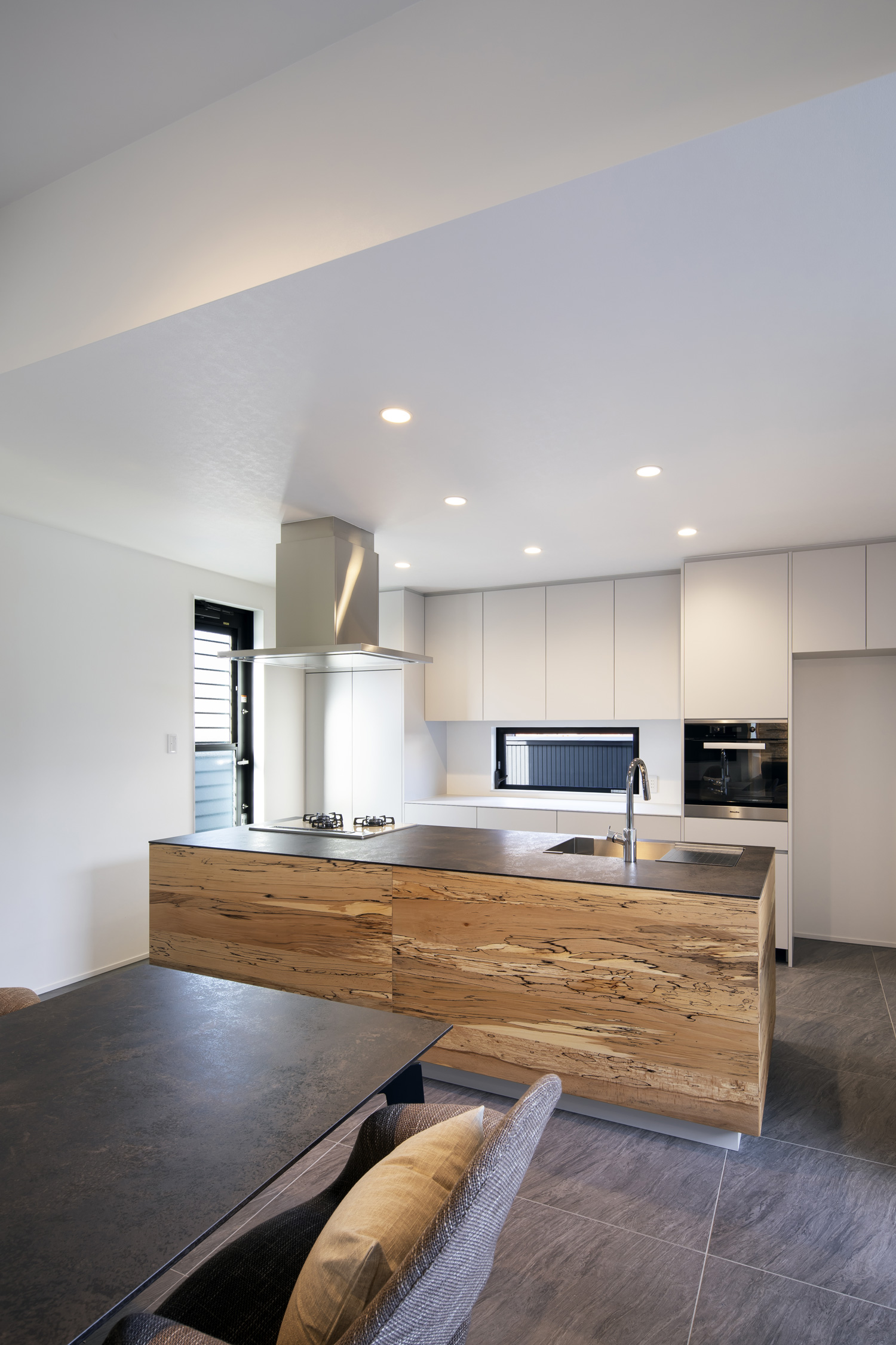 木材を使用し、背面のカップボードが壁の色と統一されたアイランドキッチン・デザイン住宅 注文住宅・デザイン住宅建築実例_『CASE657 La scene』_キッチン