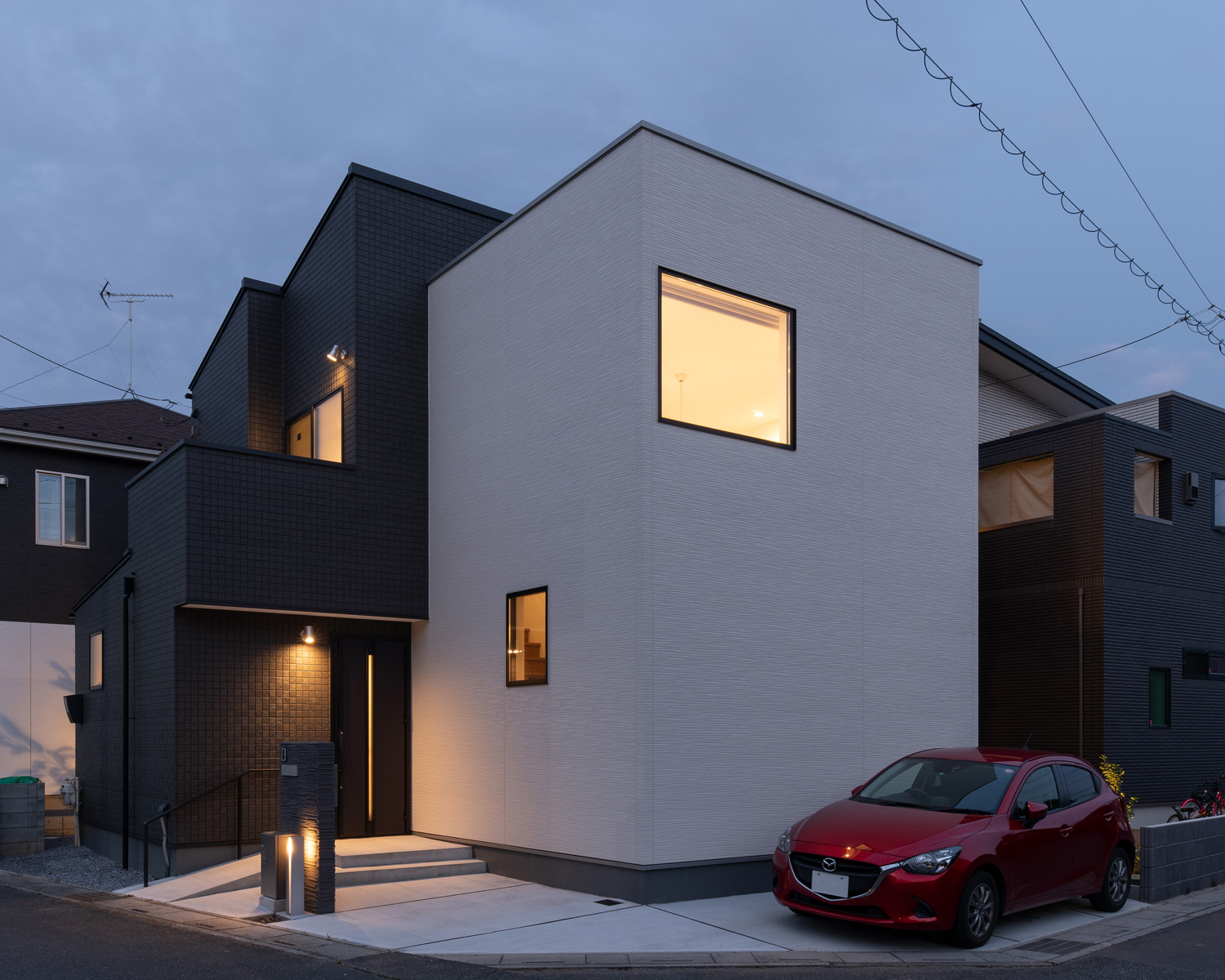 玄関ポーチが照明で照らされた、白と黒の外壁の住宅・デザイン住宅 注文住宅・デザイン住宅建築実例_『CASE658 connecting terminal』_外観