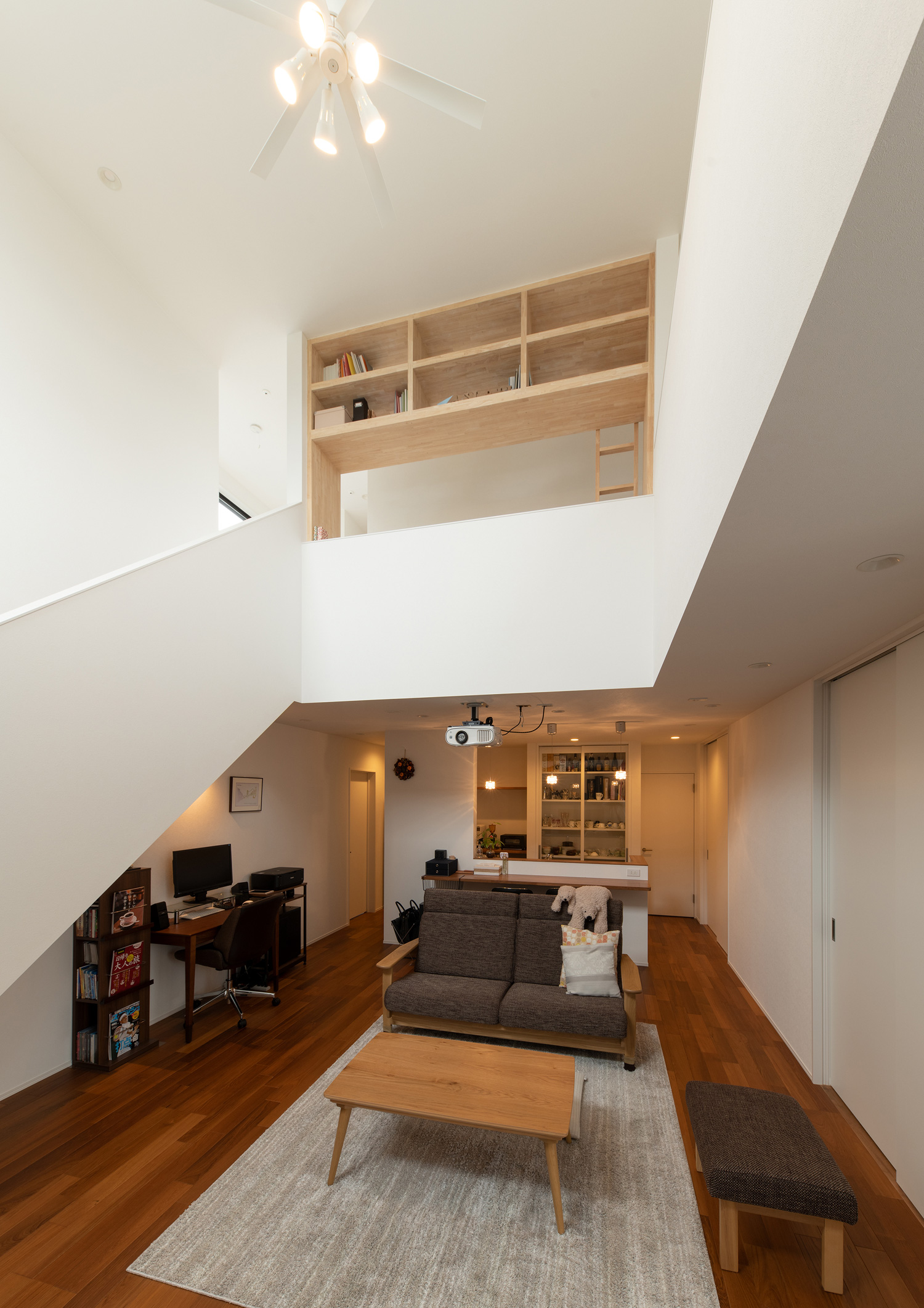 吹き抜けに面した二階に木の本棚がある様子・デザイン住宅 注文住宅・デザイン住宅建築実例_『CASE658 connecting terminal』_LDK