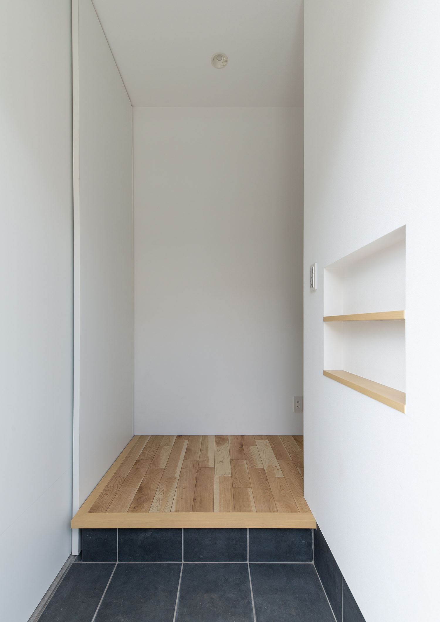 白い壁に囲まれた黒いタイル張りの玄関・デザイン住宅 注文住宅・デザイン住宅建築実例_『CASE660 Marine et grille』_玄関