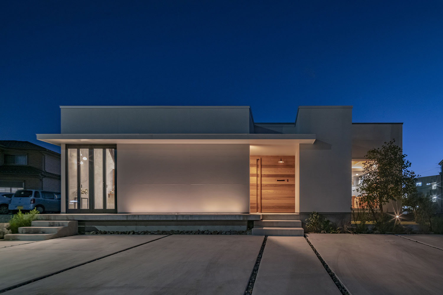 白い外壁に木目の壁が見える住宅がライトアップされた様子・デザイン住宅 注文住宅・デザイン住宅建築実例_『CASE661 環(めぐる)いえ』_外観