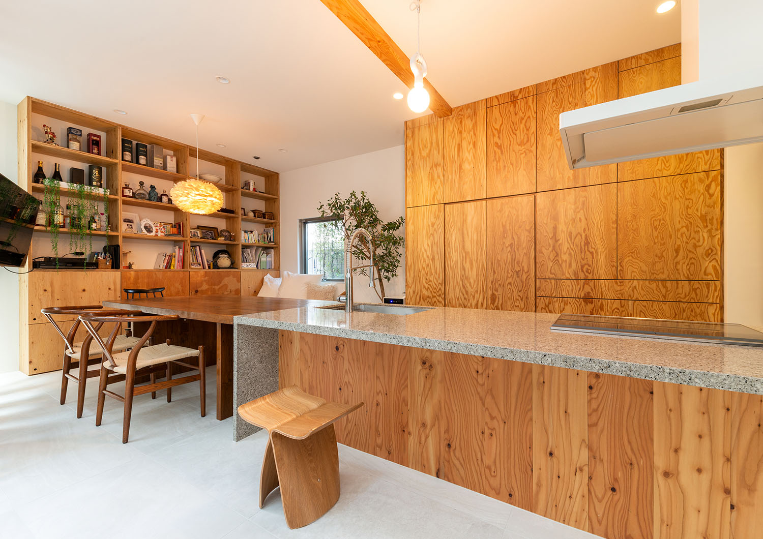 キッチンとダイニングテーブルがある空間の、壁一面に木の棚がある様子・デザイン住宅 注文住宅・デザイン住宅建築実例_『CASE665 LUCE』_LDK