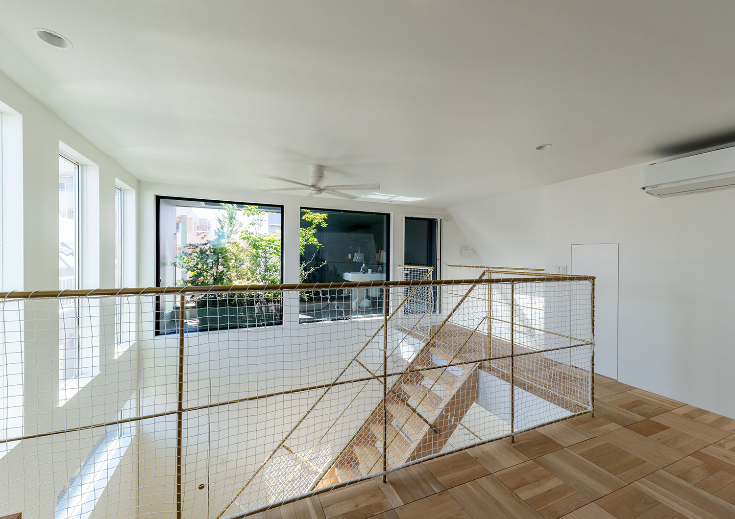 吹き抜けに面する部分にネットが張られた、木目の床の廊下・デザイン住宅 注文住宅・デザイン住宅建築実例_『CASE665 LUCE』_廊下