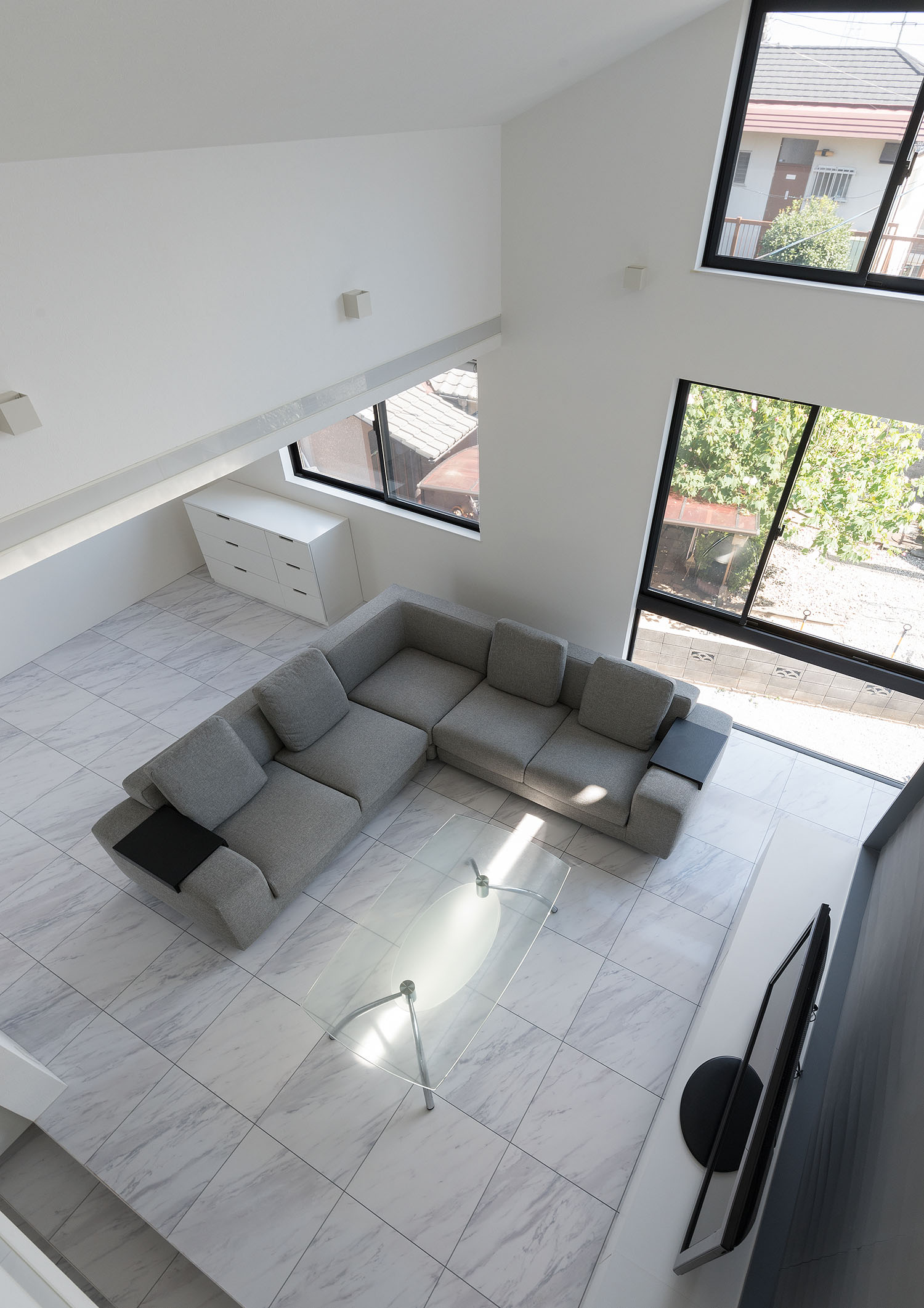 吹き抜けの二階からグレーのL字ソファがある一階を見下ろした様子・デザイン住宅 注文住宅・デザイン住宅建築実例_『CASE667 コントラスト』_LDK