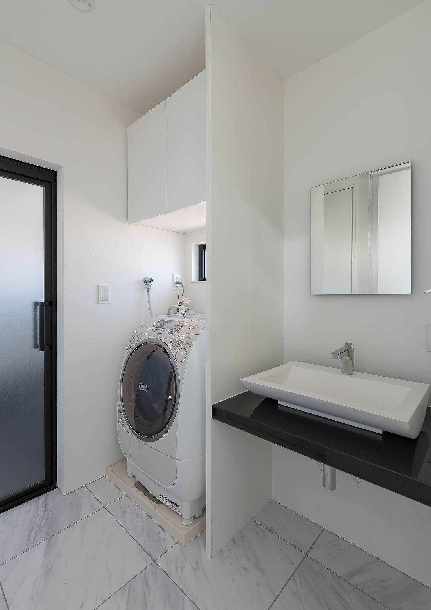 洗濯機がそばにある大理石風の床の洗面所・デザイン住宅 注文住宅・デザイン住宅建築実例_『CASE667 コントラスト』_浴室・洗面所