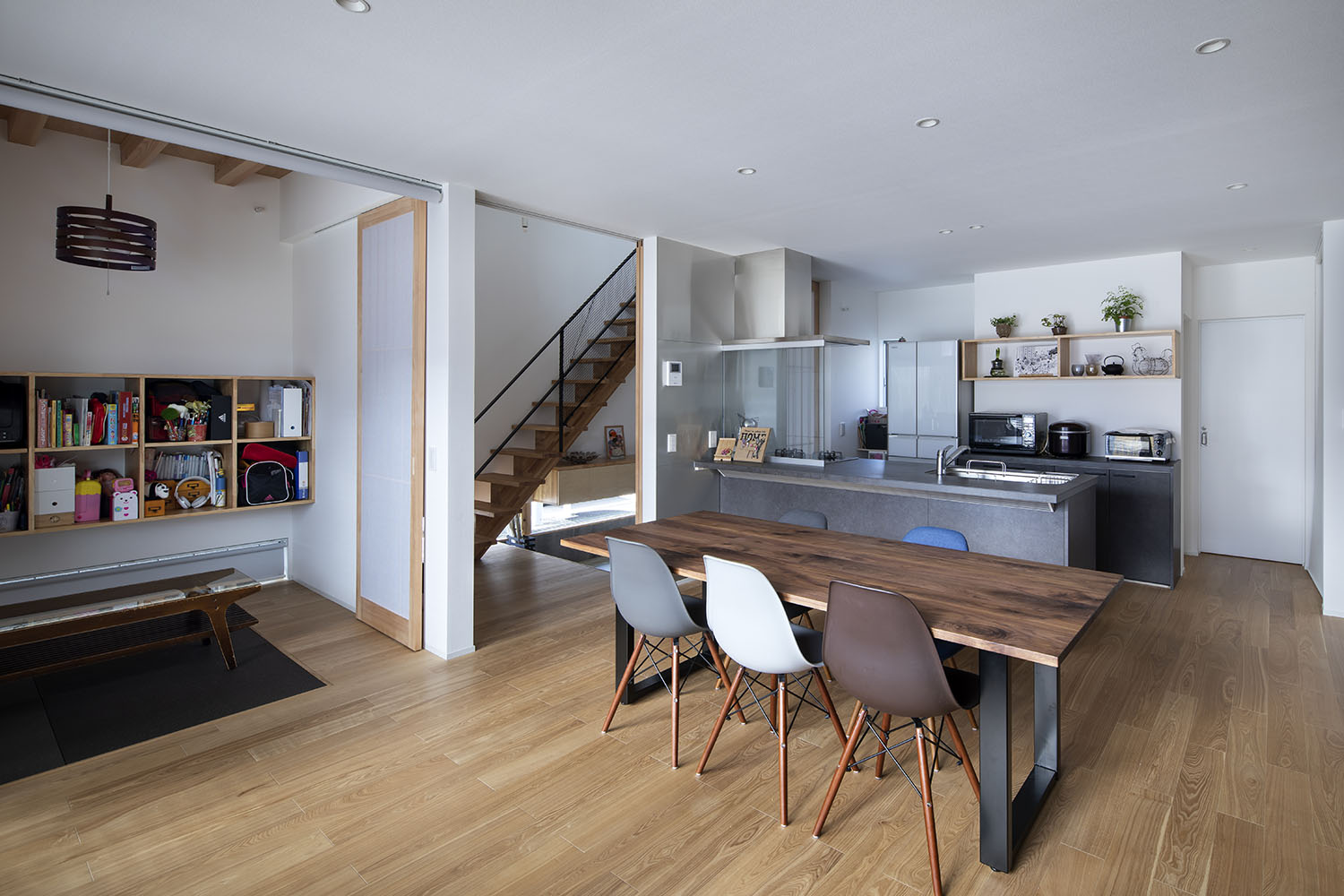 グレーのペニンシュラキッチンの向かいに木のダイニングテーブルが置かれた様子・デザイン住宅 注文住宅・デザイン住宅建築実例_『CASE669 ludique』_LDK