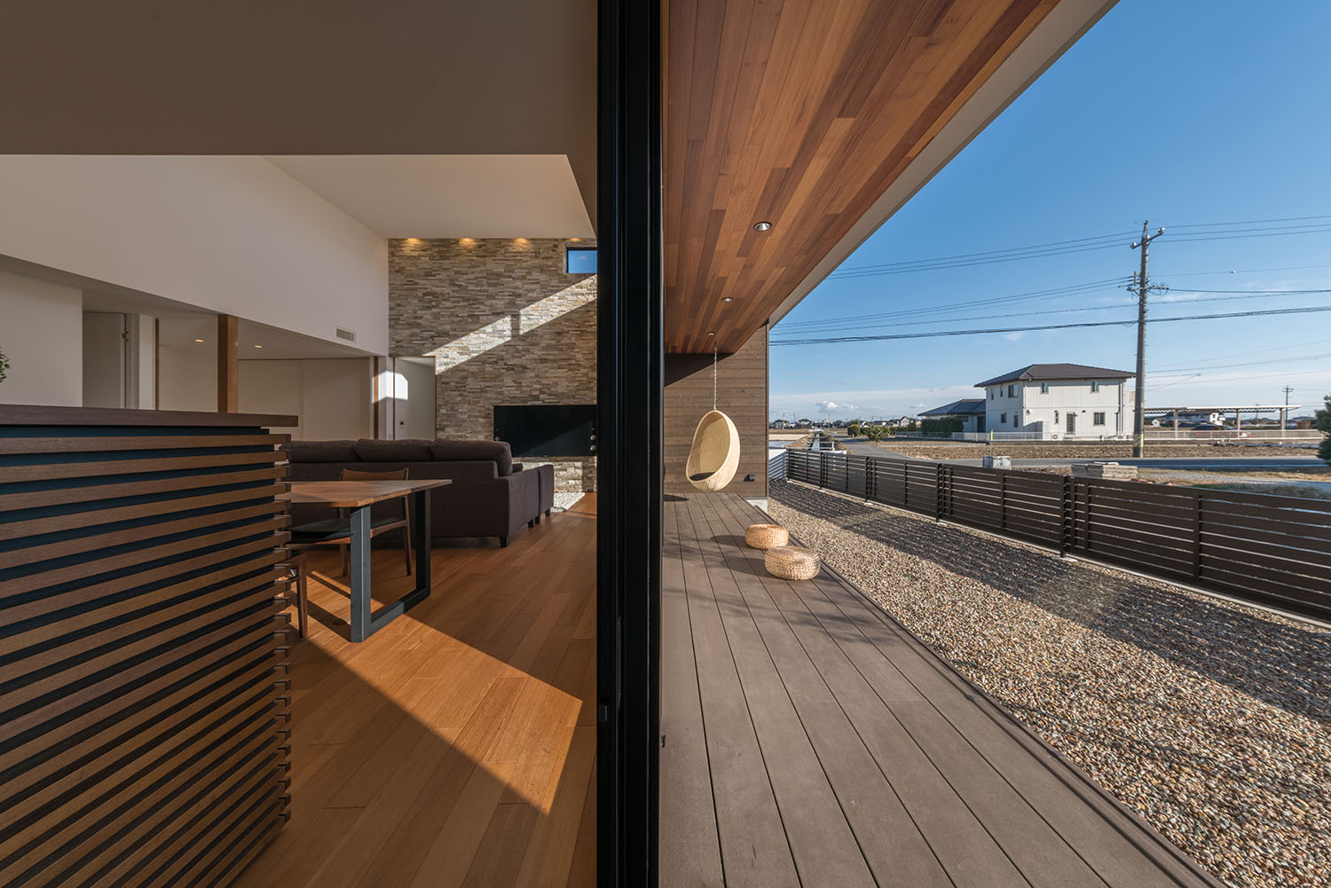 LDKと、木の軒天井のテラスがフラットに繋がる様子・デザイン住宅 注文住宅・デザイン住宅建築実例_『CASE671 実りの平屋』_テラス・バルコニー