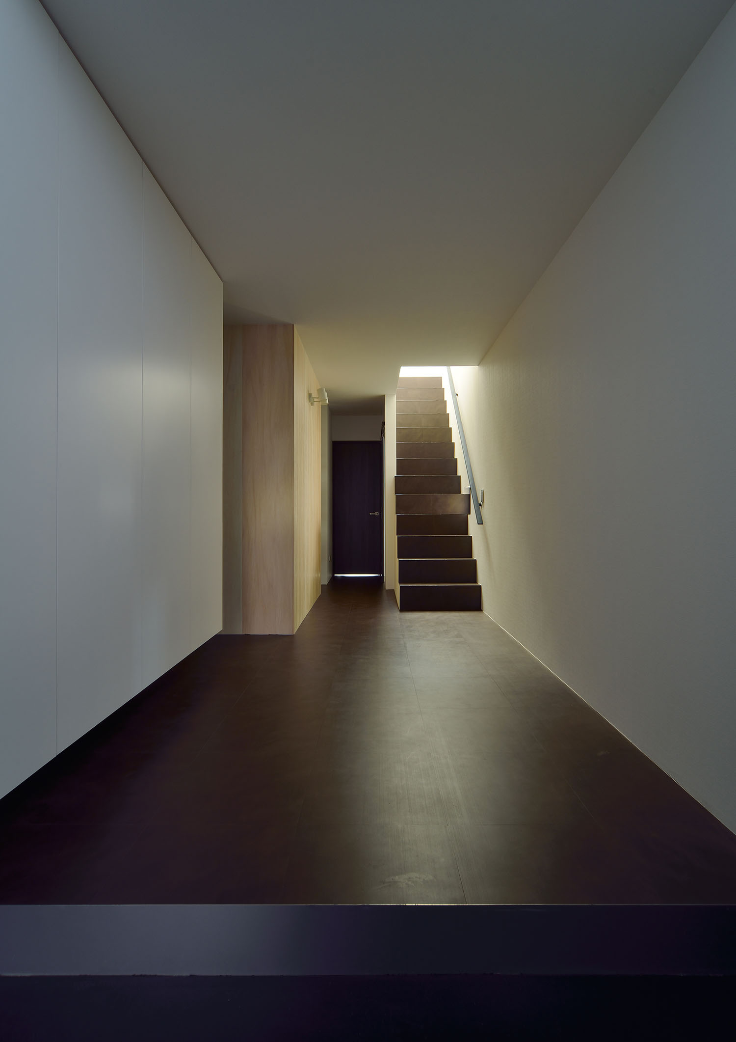 黒い玄関の先に、黒い床の廊下や階段が広がっている様子・デザイン住宅 注文住宅・デザイン住宅建築実例_『CASE676 箱を包む小屋裏』_玄関