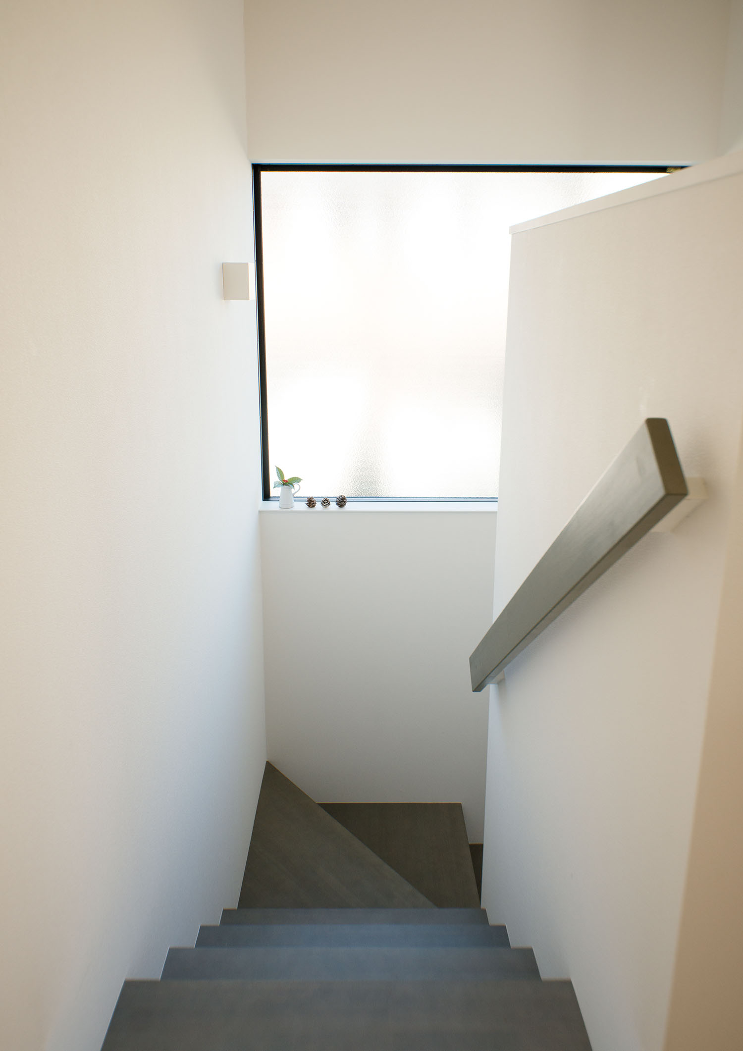 白い壁に囲まれグレーの手すりが設けられたグレーの回り階段・デザイン住宅 注文住宅・デザイン住宅建築実例_『CASE677 中庭が繋ぐ家族の気配』_階段